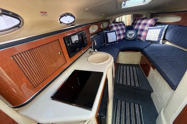 2003 Sea Ray 260 Sundancer cabin interior with kitchenette and cozy seating area.