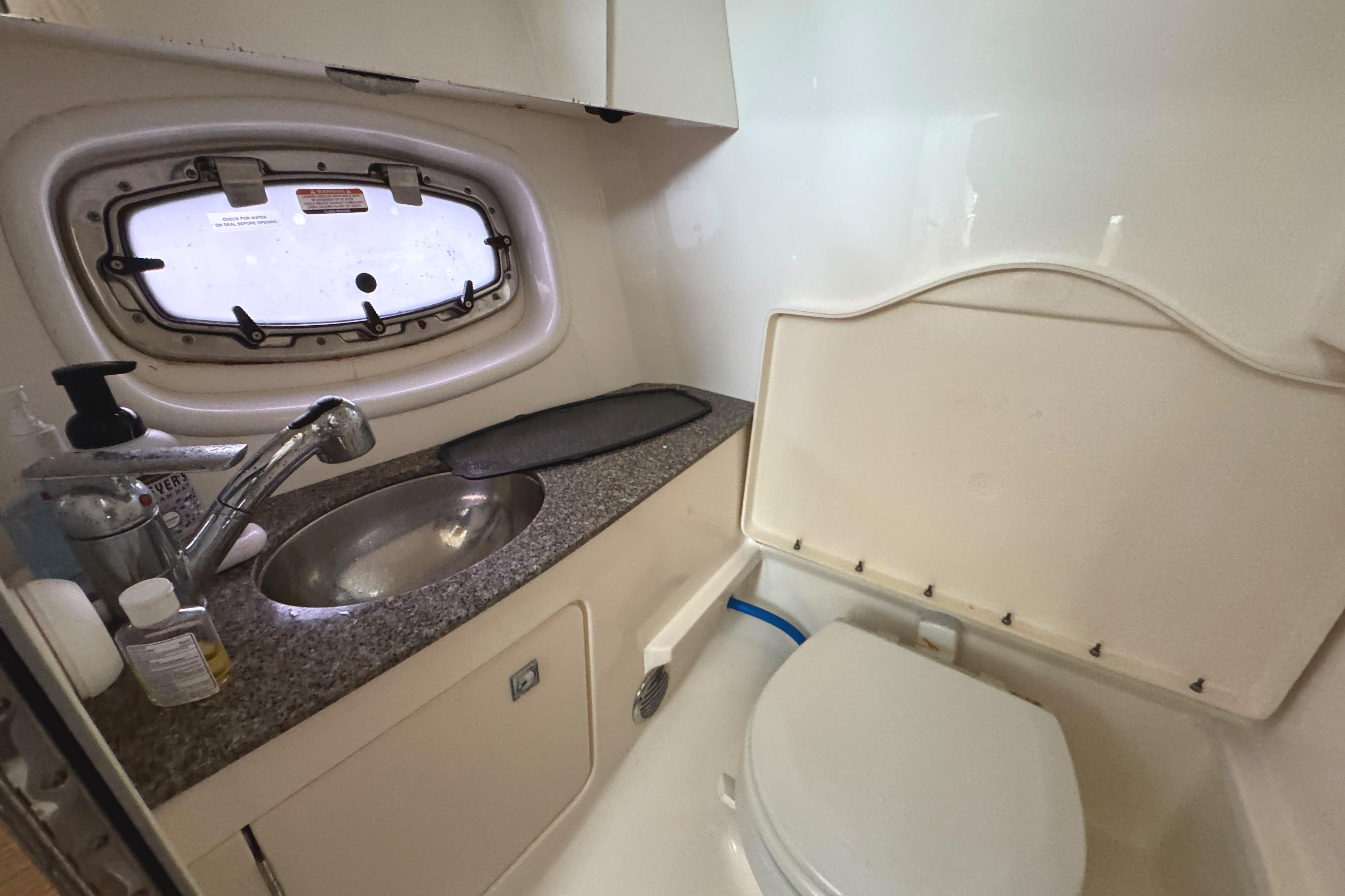 2012 Chaparral 327 SSX boat bathroom with sink, toilet, and porthole window.
