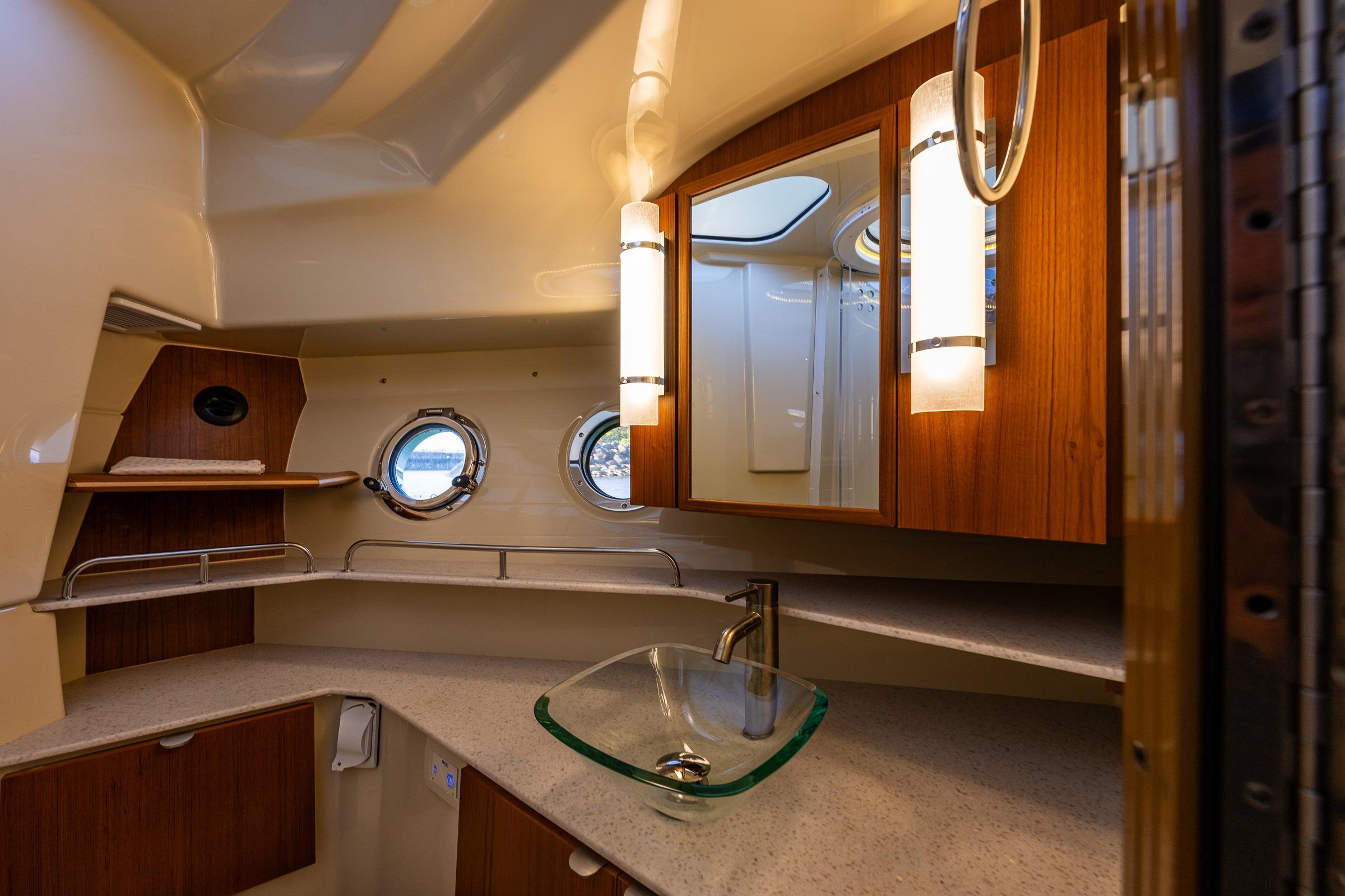 Luxurious bathroom interior of 2020 Ranger Tugs R-41 CB with modern fixtures and porthole windows.