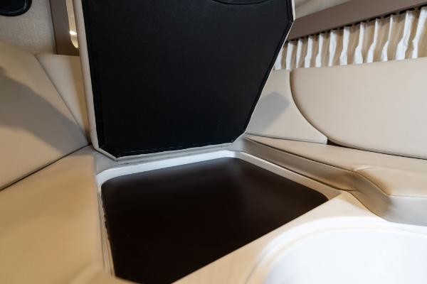 2016 Regal 28 Express interior storage compartment with beige seating and black lid.