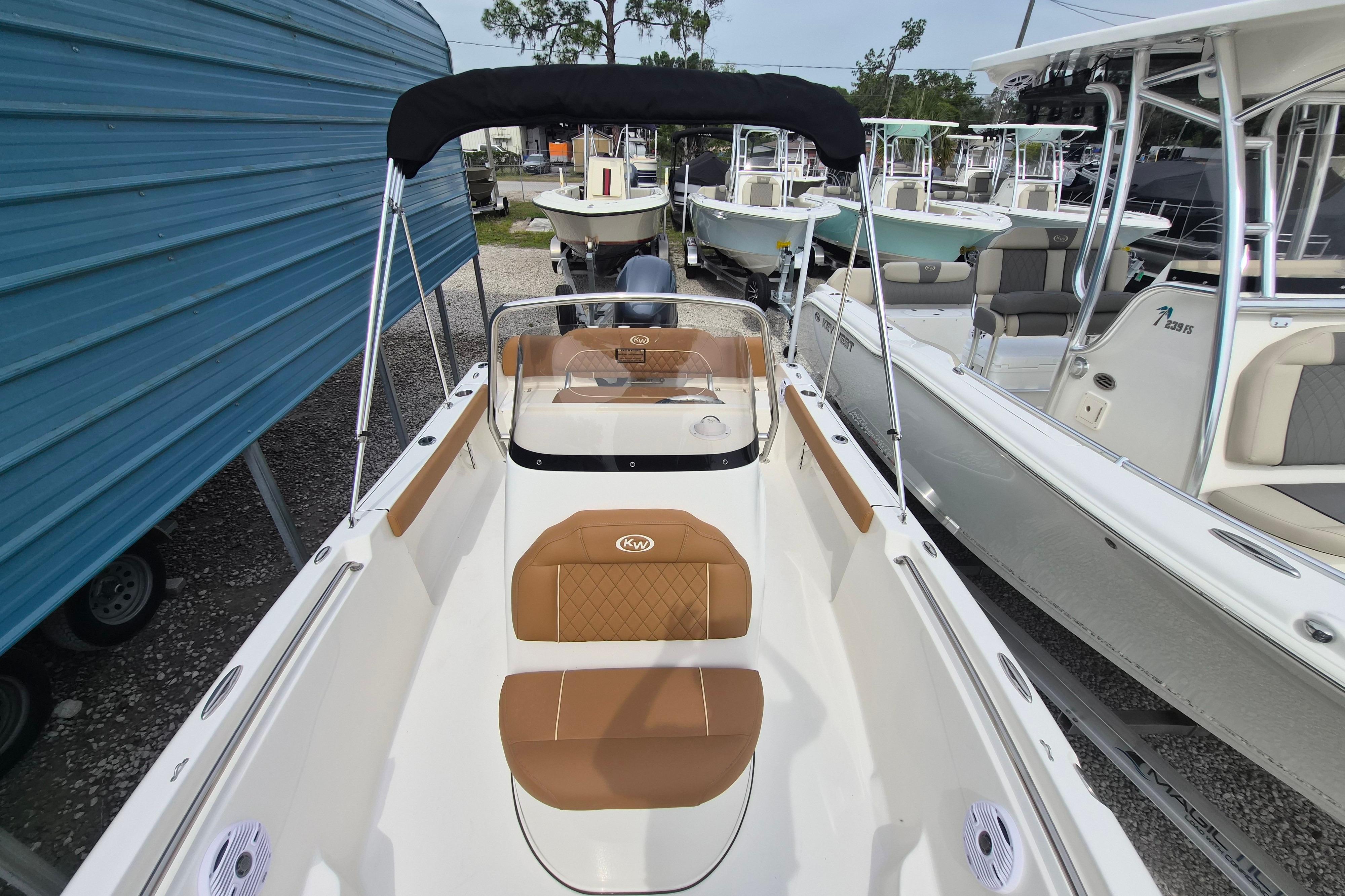 2026 Key West 189 FS boat with tan seating and black canopy in a marina.