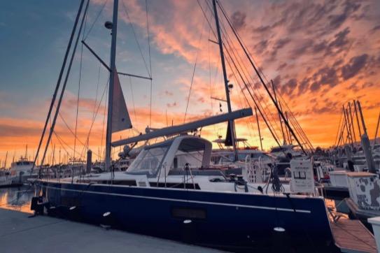 2022 Beneteau Oceanis Yacht 54 docked at sunset, showcasing elegant design and vibrant sky.