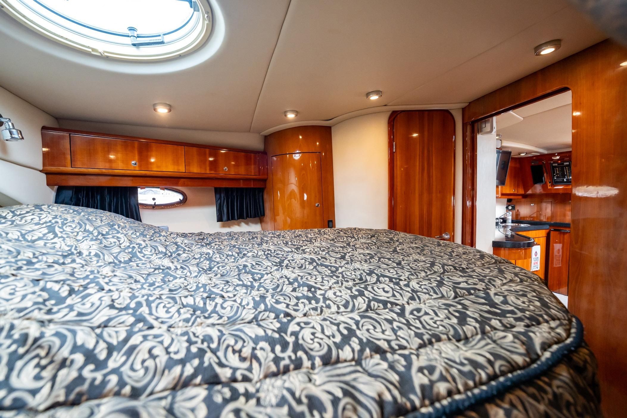 Luxurious interior of 2008 Regal Commodore 4460 yacht with elegant wood finishes and plush bedding.