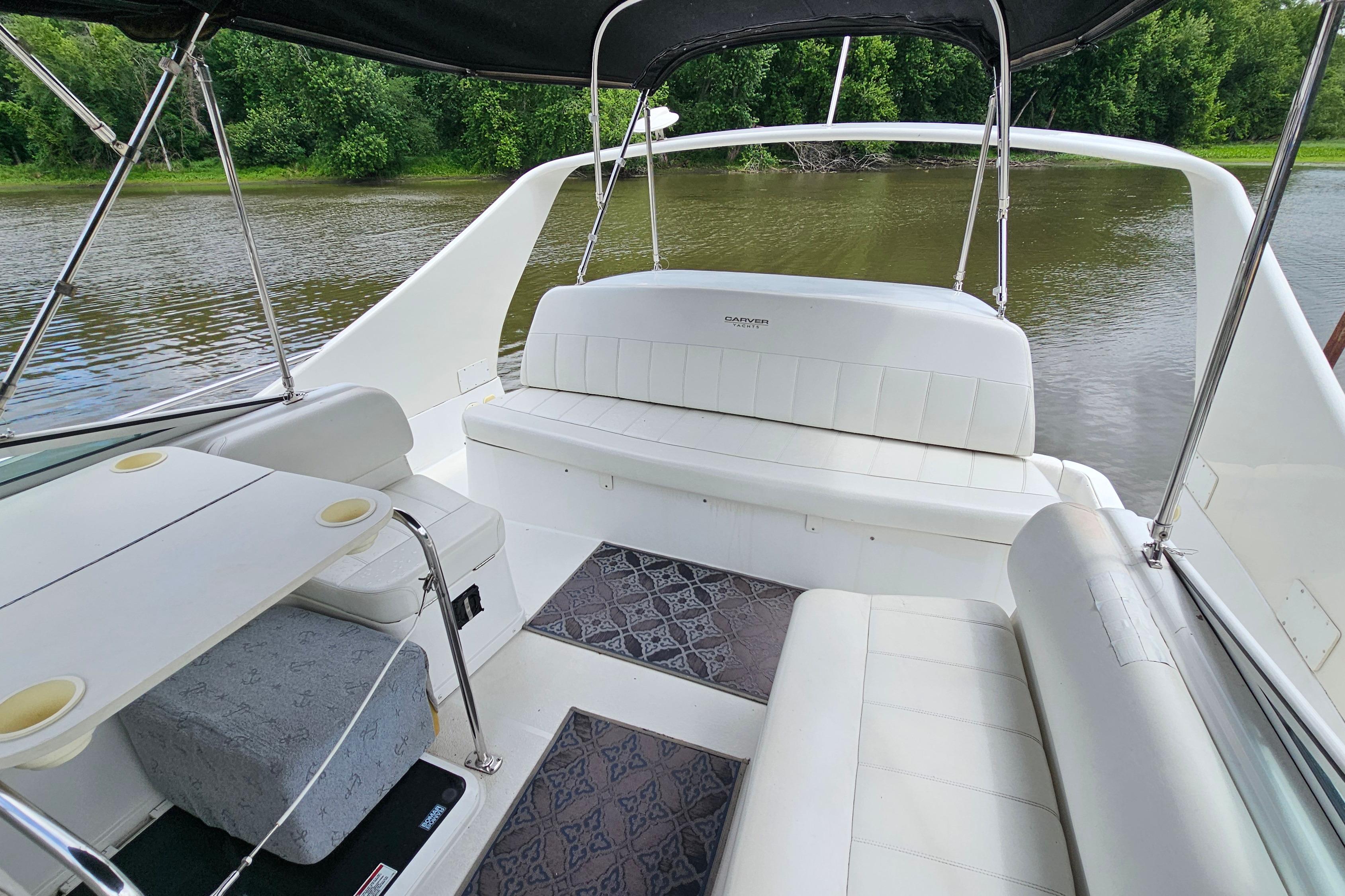 1999 Carver 350 Mariner boat interior with white seating, table, and scenic river view.