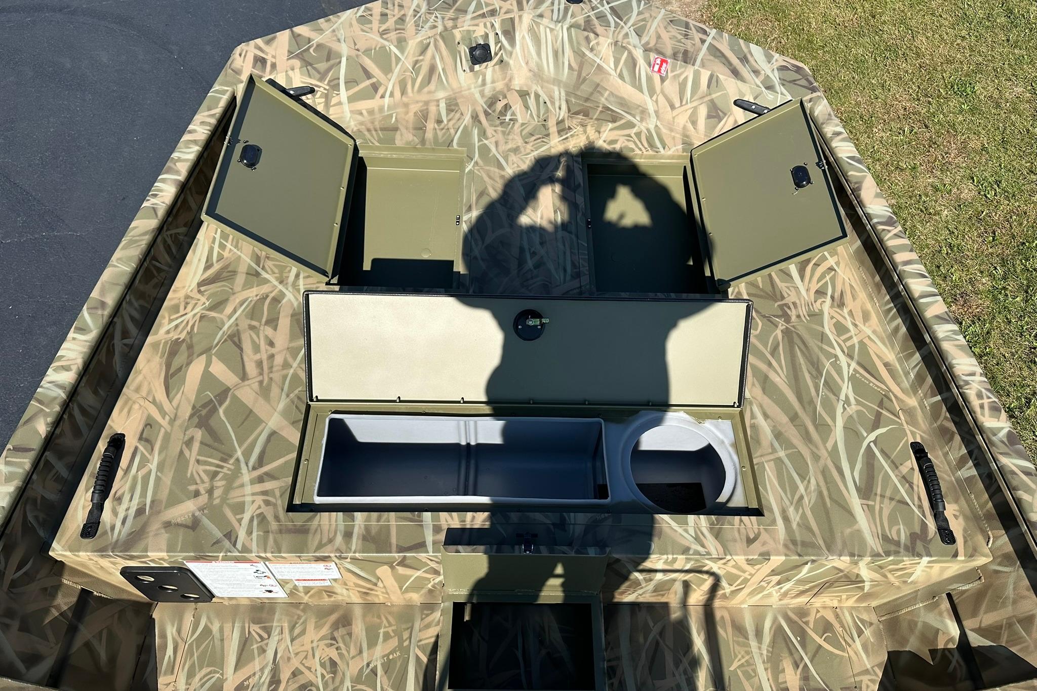 2026 Lowe Roughneck 2070CC boat interior with open storage compartments and camouflage design.