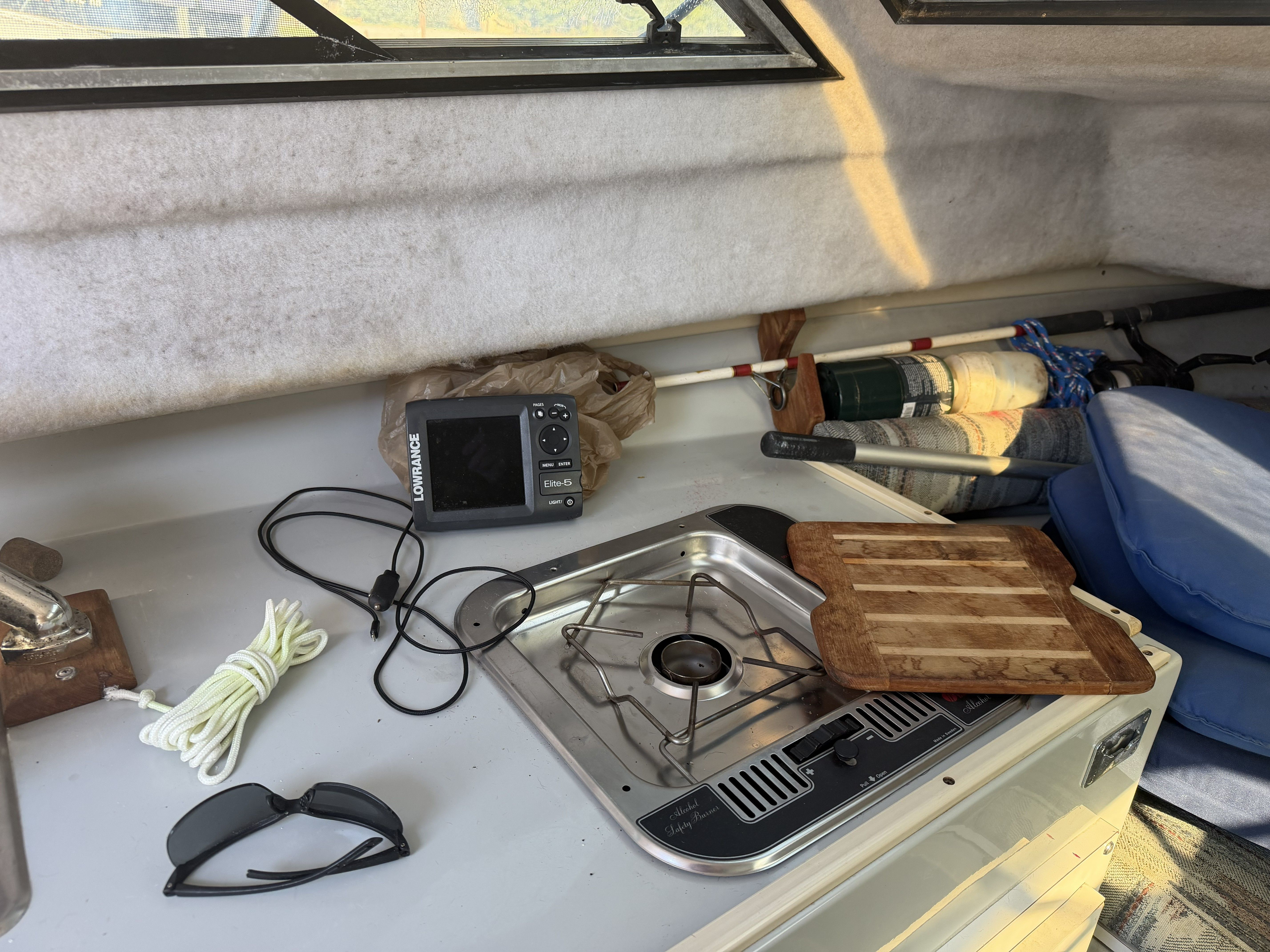 Interior of a 1989 Wellcraft 250 Sportsman with stove, cutting board, and fishing rods.