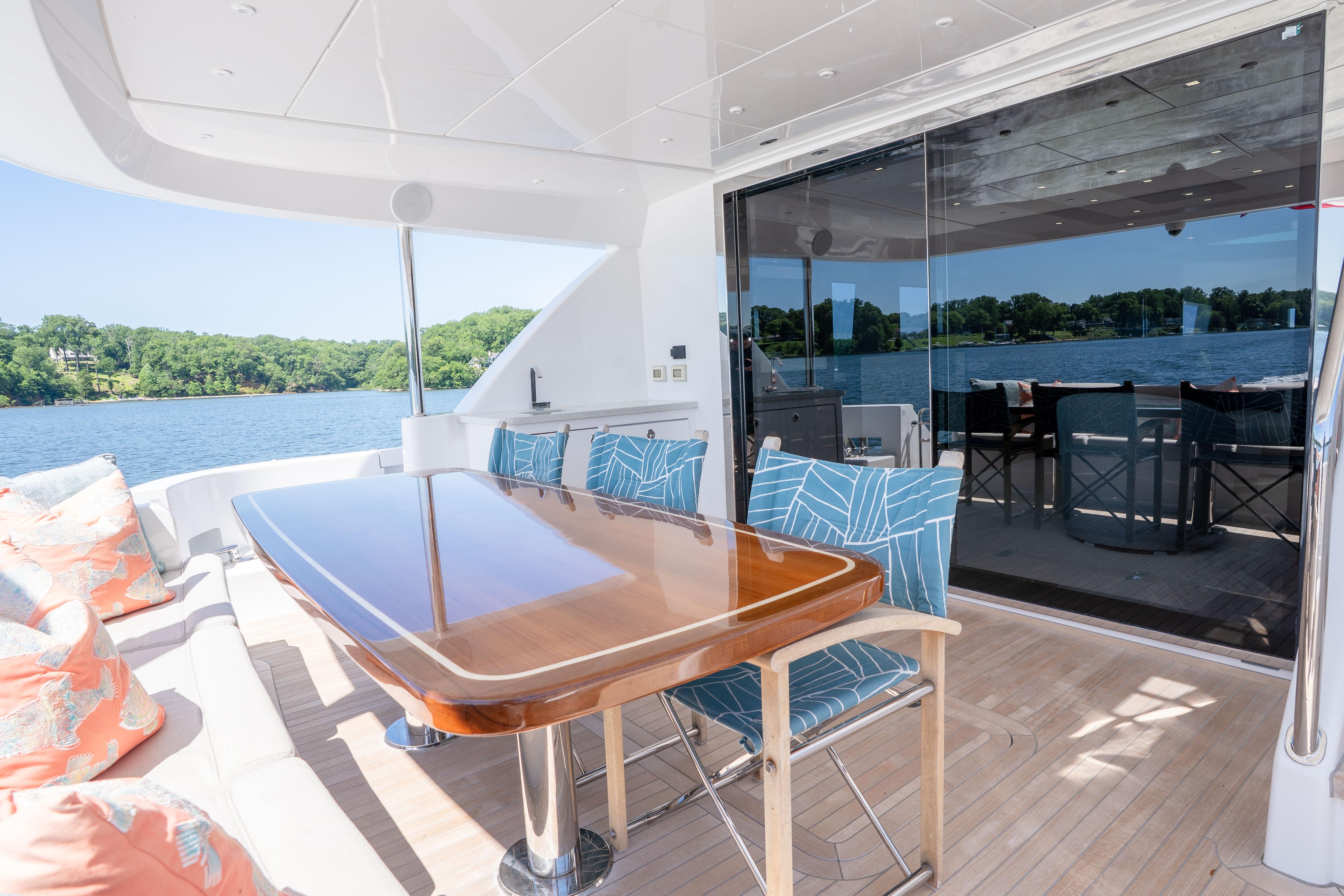 Luxurious 2021 Hatteras M75 Panacera yacht deck with elegant dining area and scenic water view.