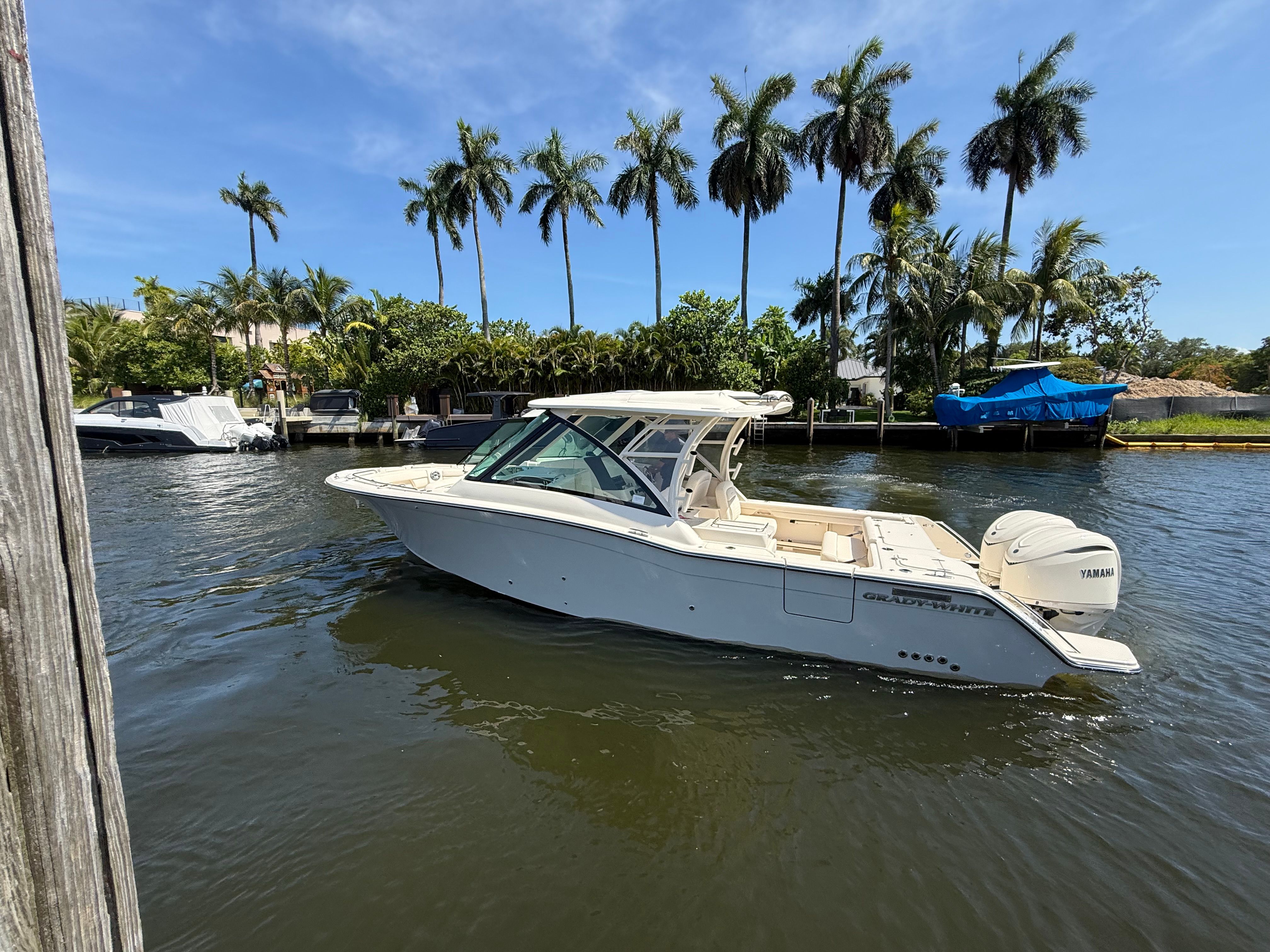 2027 Grady-White Freedom 325 on a calm waterway with palm trees in the background.