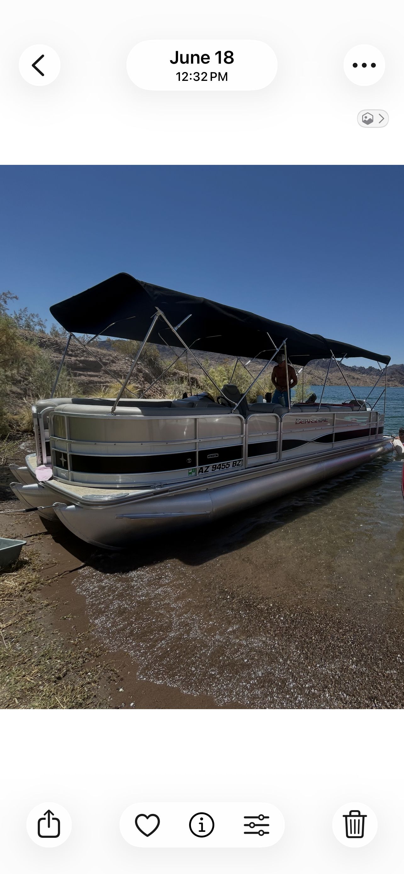 A 2018 Berkshire 24RFX CTS pontoon boat with a canopy, docked at a lakeside shore.