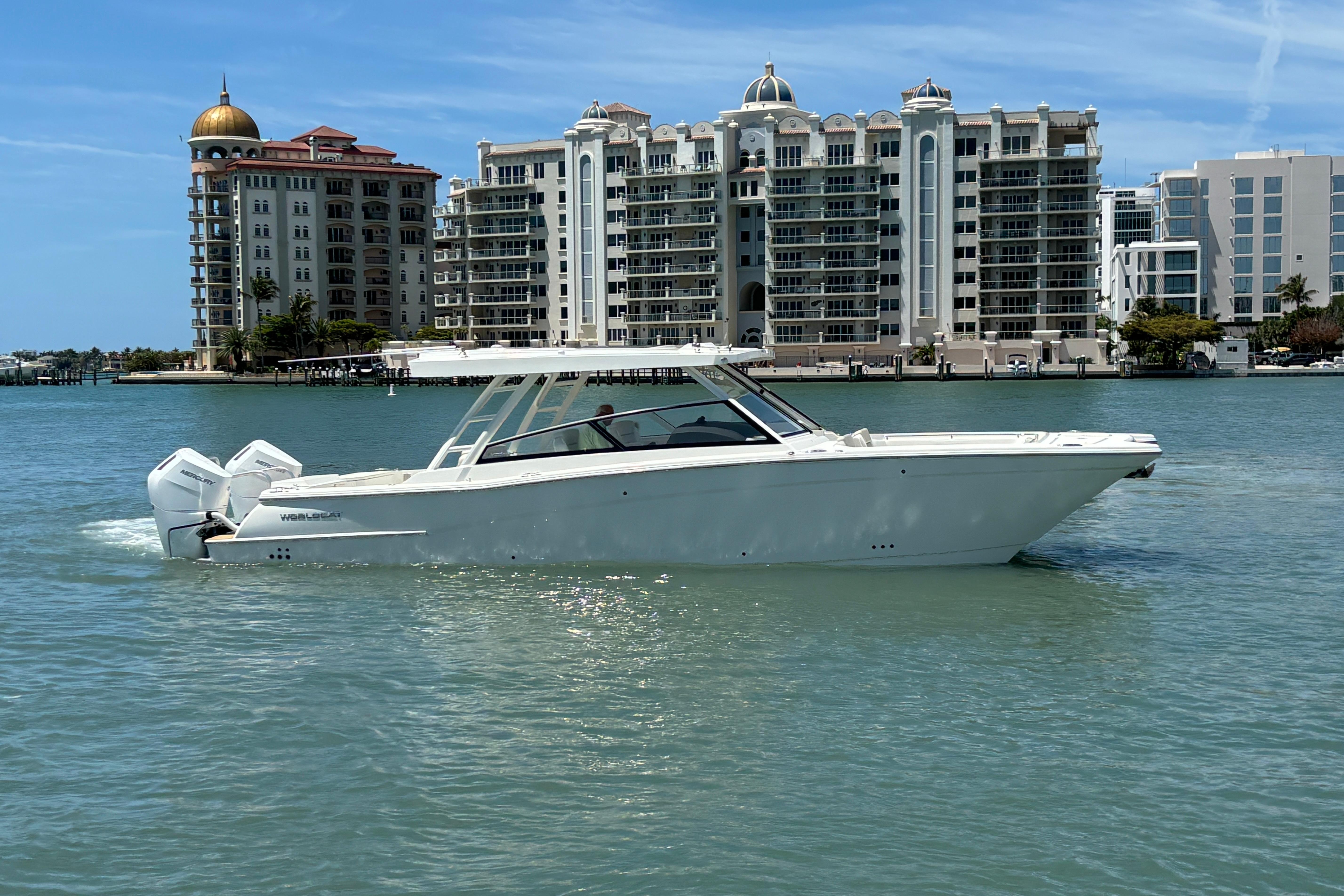 2026 World Cat 400 DC-X Island boat cruising near luxury waterfront buildings.