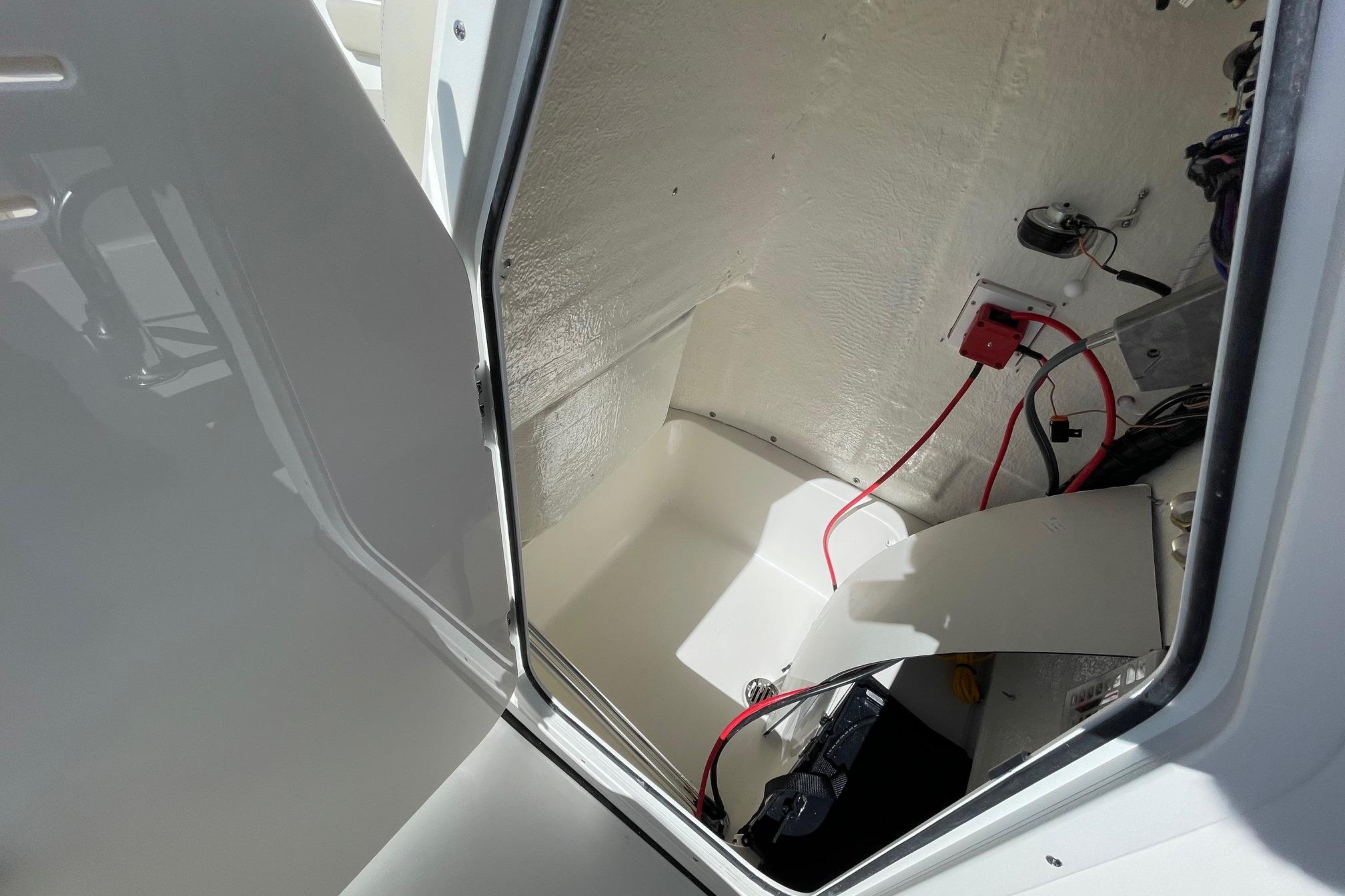Interior view of 2026 Key West 203 FS boat compartment with wiring and battery.
