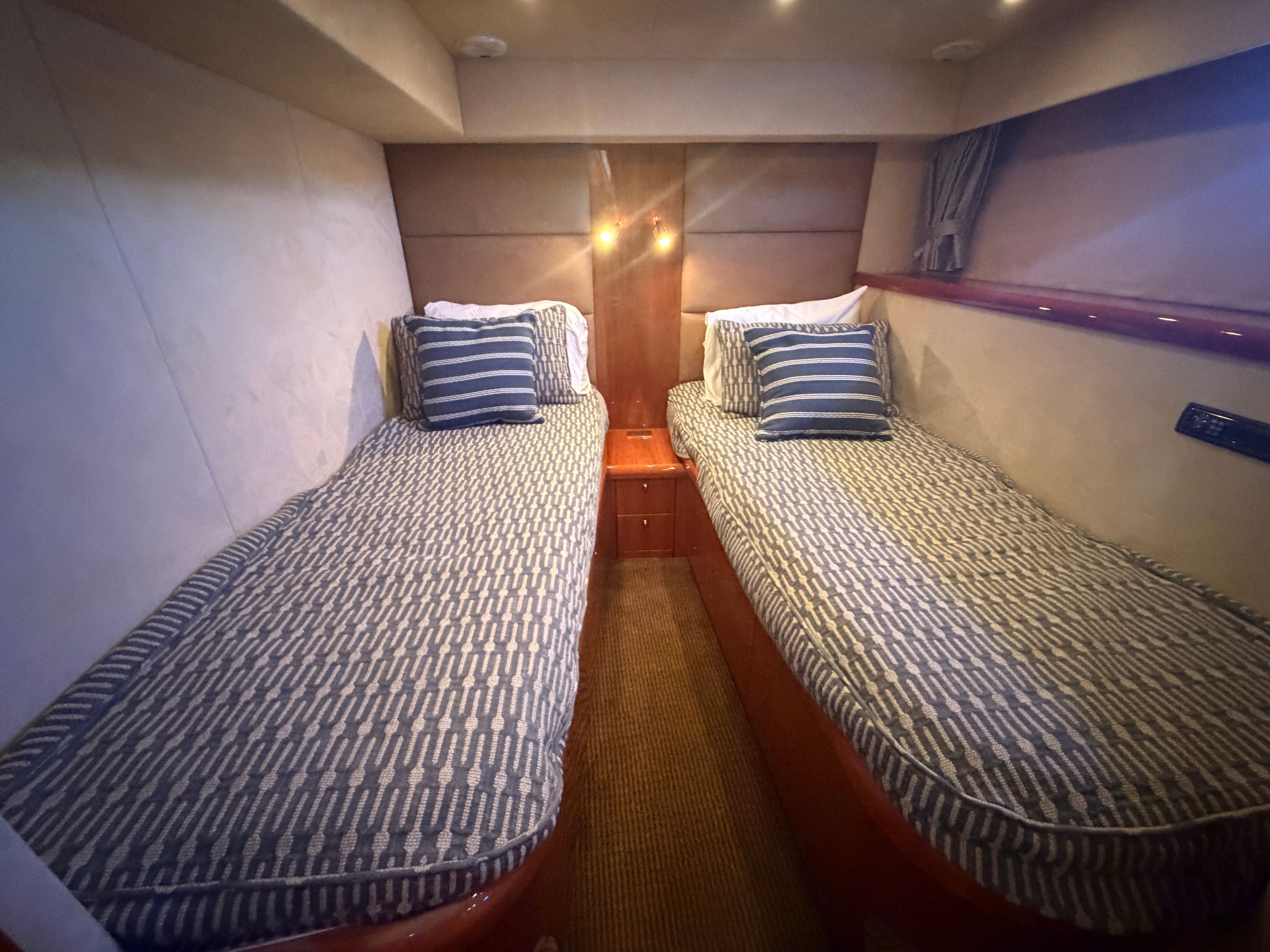 Two single beds in a cozy cabin with striped bedding and wooden furnishings.