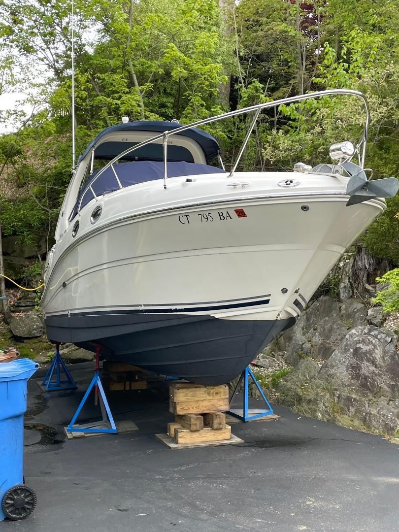 A 2005 Sea Ray Sundancer 260 on a trailer, surrounded by trees.