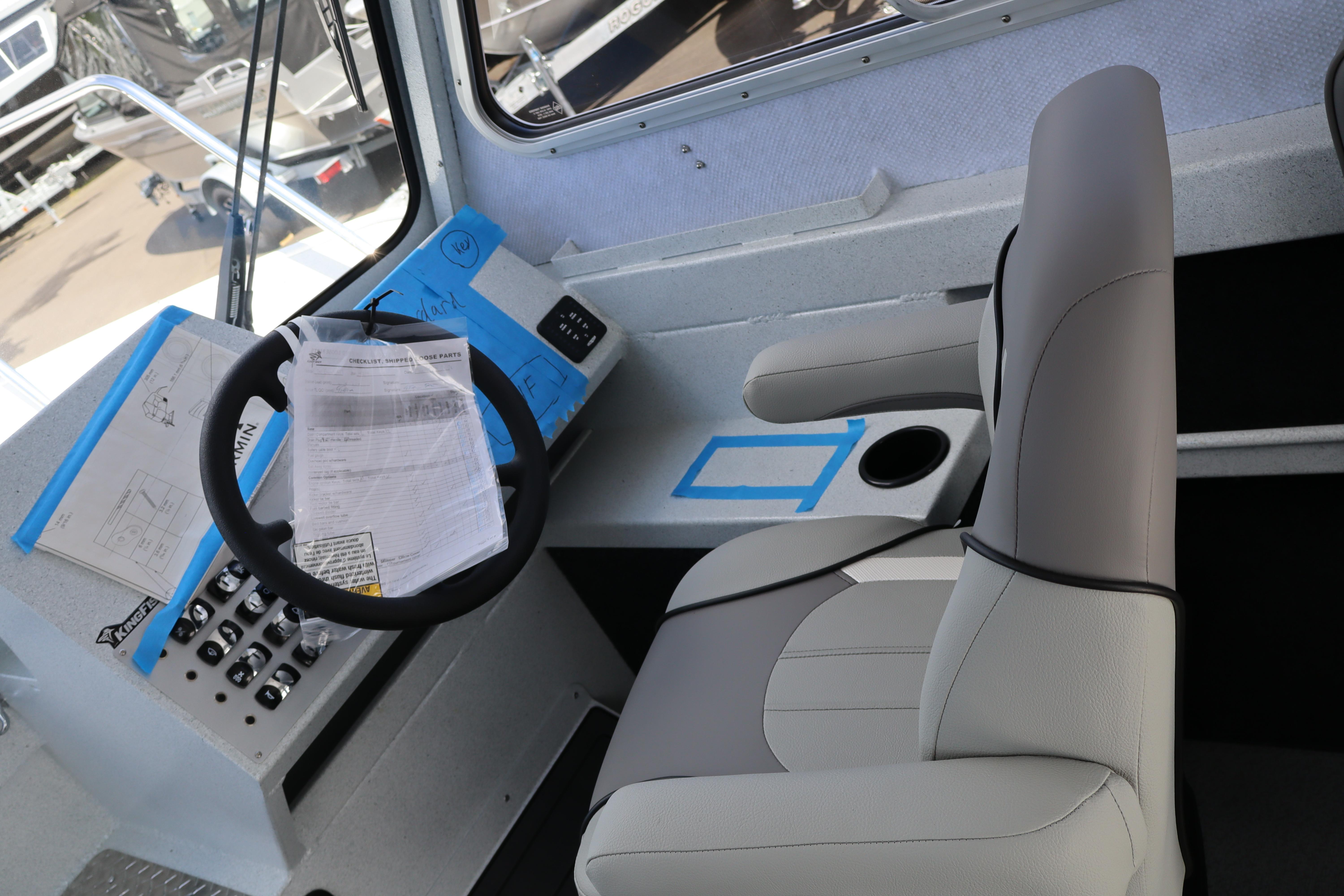 Interior of 2026 KingFisher 2425 Escape HT boat, featuring steering wheel and captain's chair.