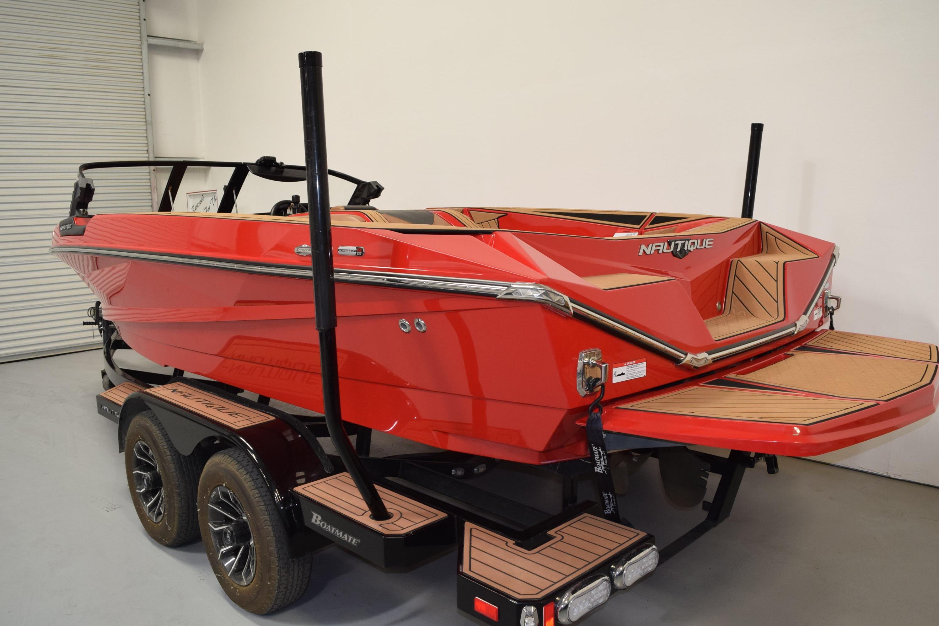 2024 Nautique Ski Nautique boat in vibrant red on a trailer in a garage.
