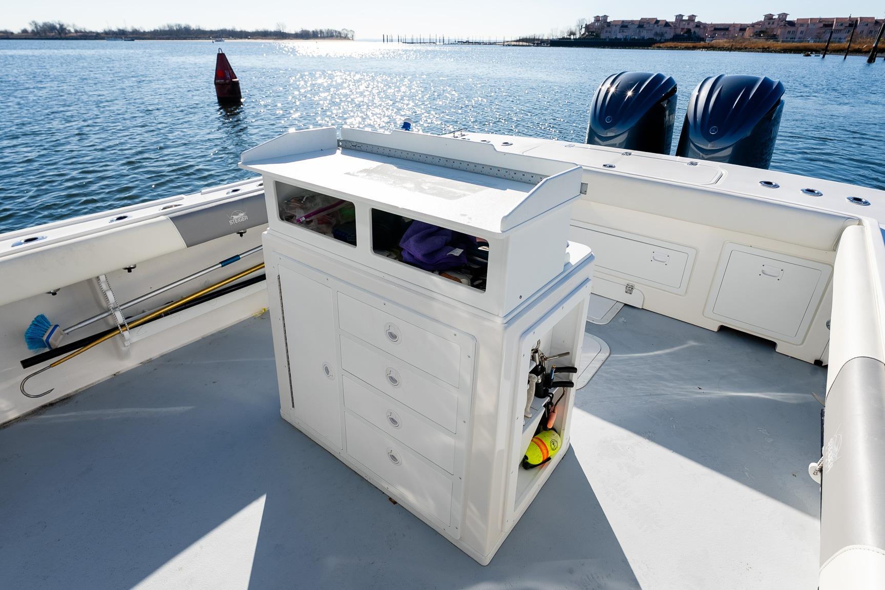 2024 Steiger Craft 31 Fisherman boat deck with storage and twin engines on a sunny day.