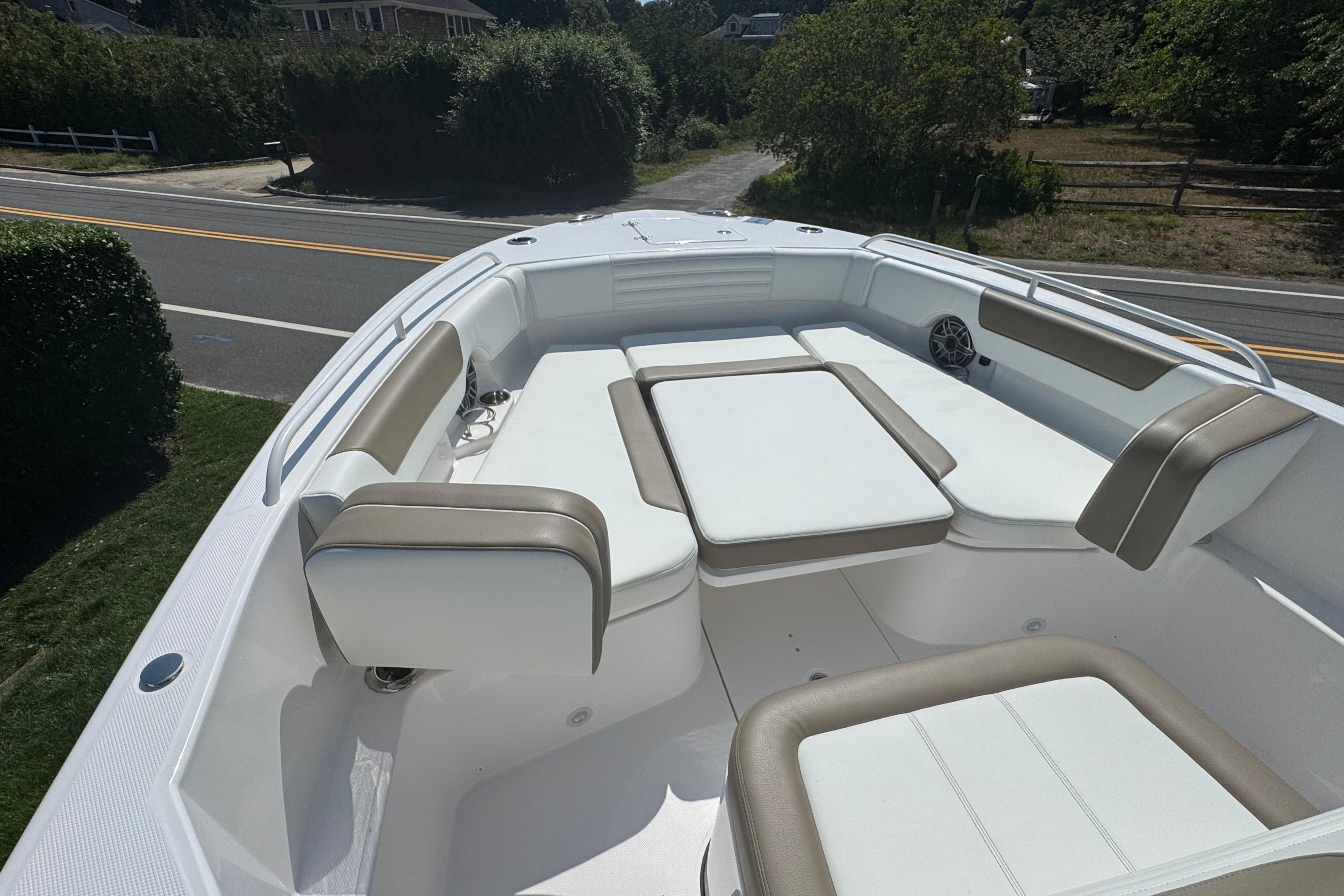 2026 Edgewater 250CC boat interior with cushioned seating and table, parked near a road.