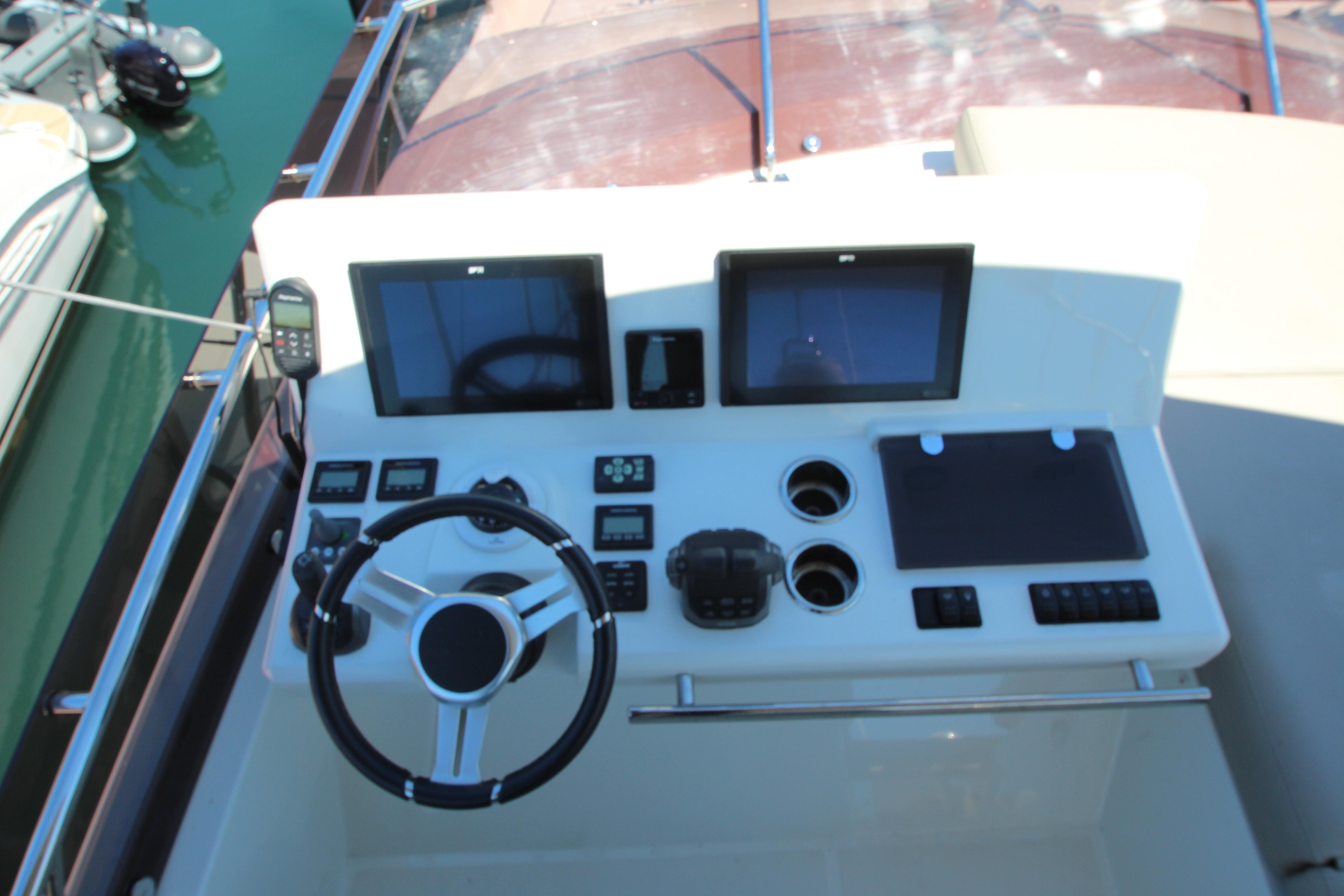 Control panel of a 2022 Prestige 520 yacht with dual screens and steering wheel.