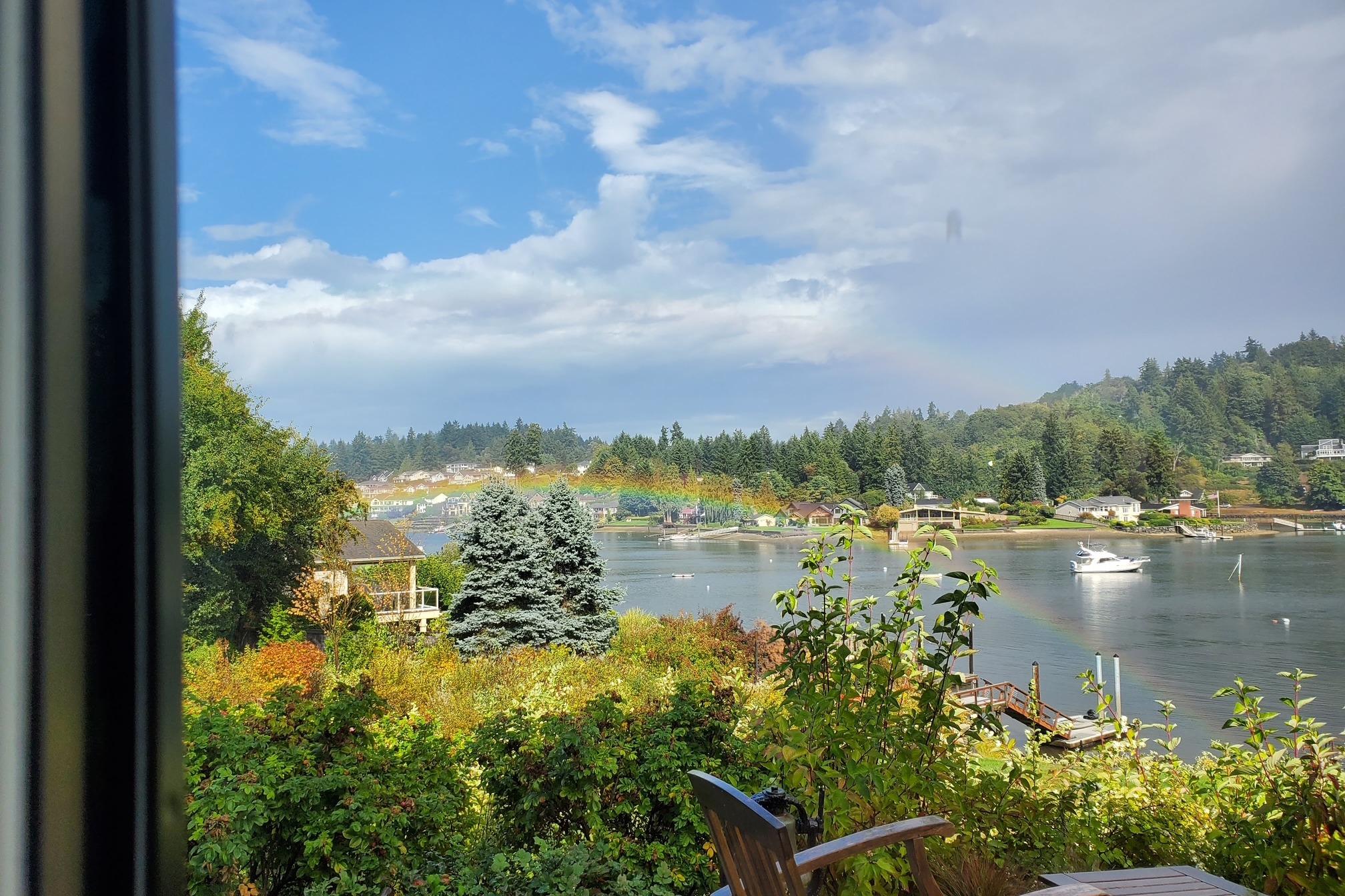 Scenic waterfront view with rainbow, featuring a 1998 Bayliner 3388 Command Bridge Motoryacht.