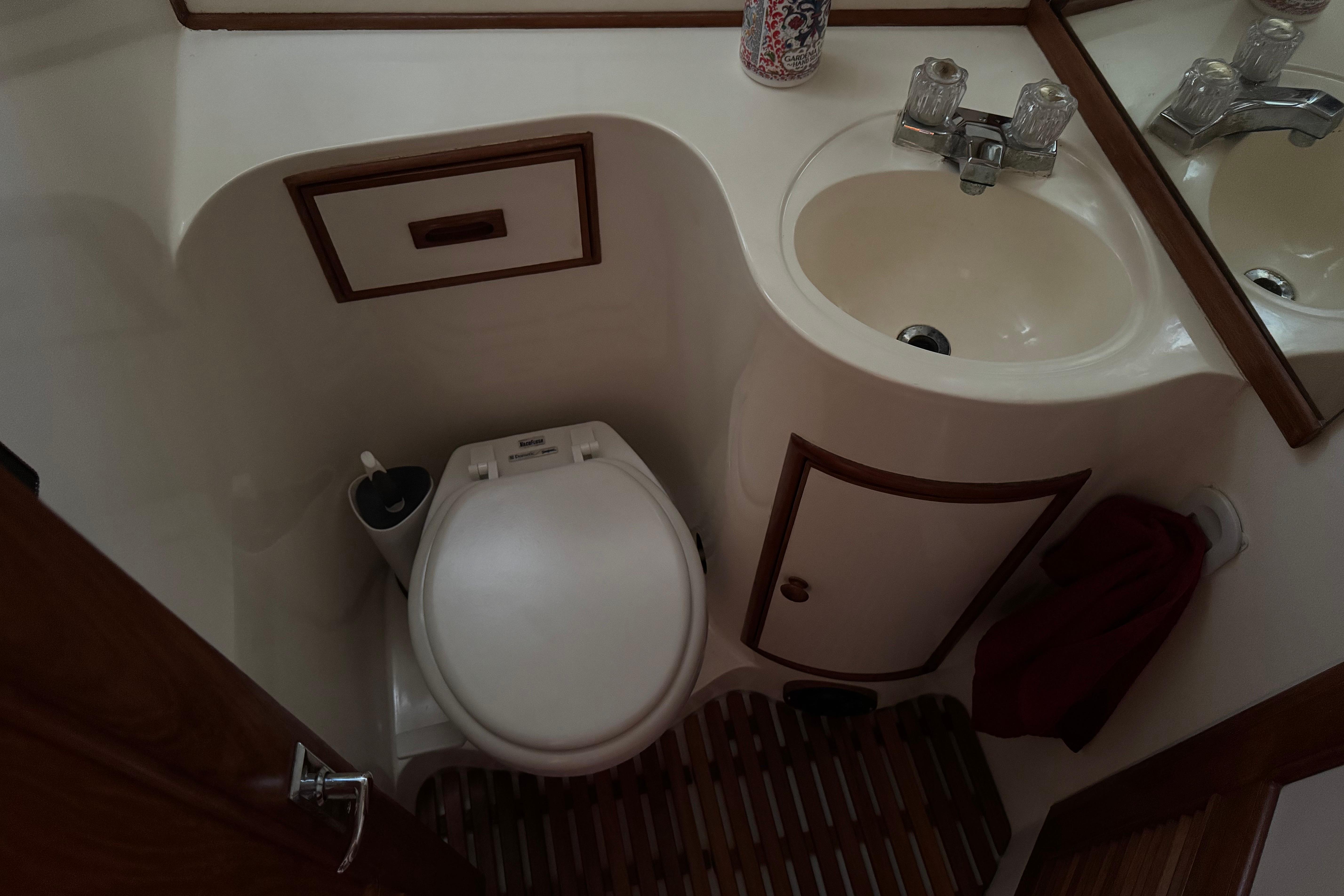 Compact bathroom in a 1987 President 37 yacht, featuring a toilet and sink.