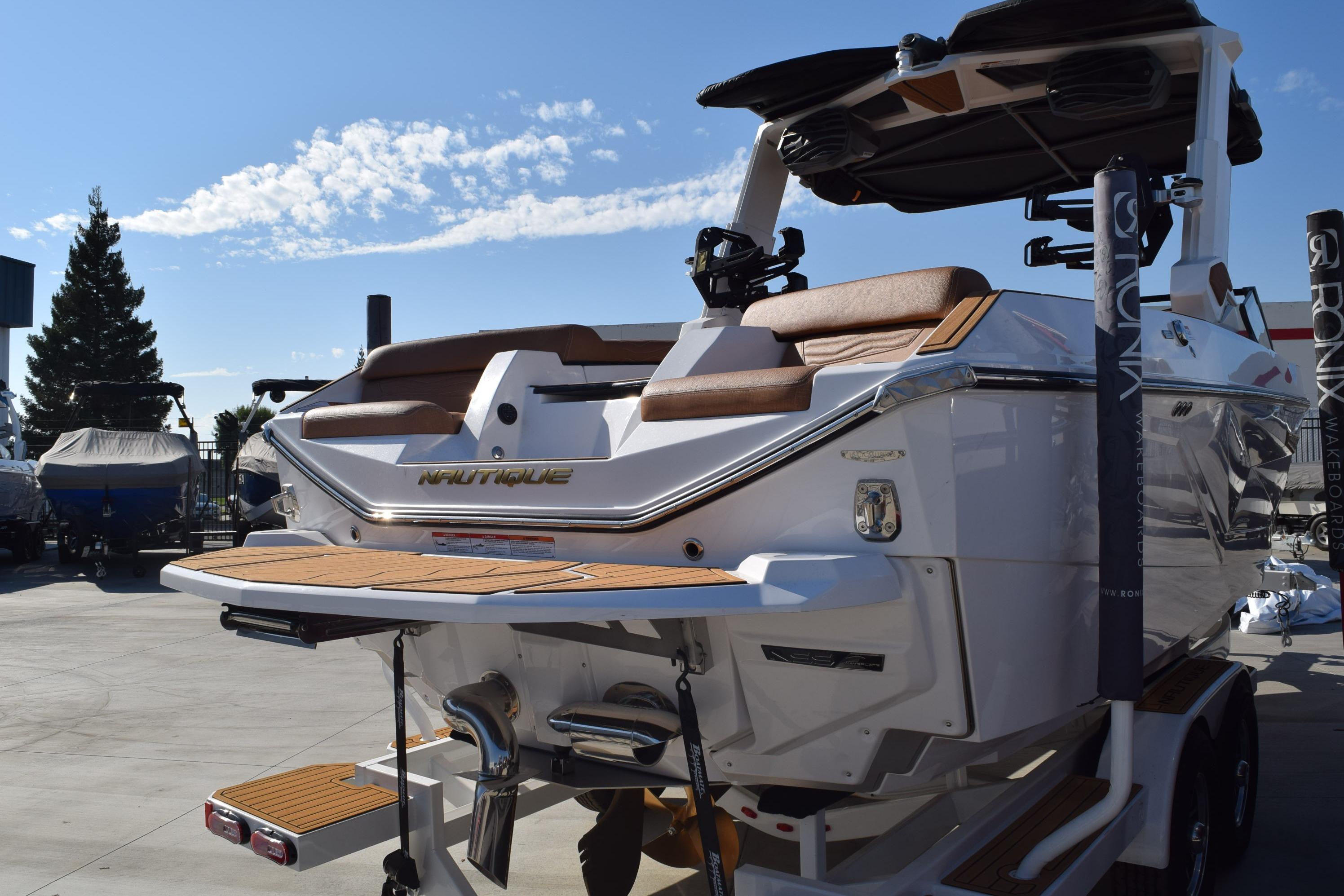 2026 Nautique Super Air Nautique G23 boat, rear view, in a sunny outdoor setting.
