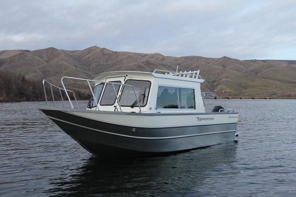 2023 Spartan 220 Maximus Pro boat on a calm lake with mountainous background.
