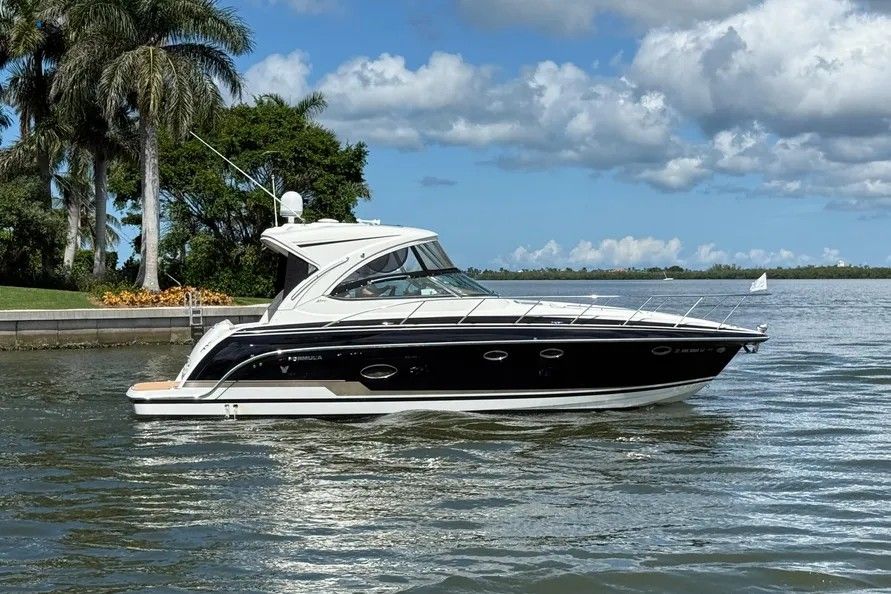 A sleek motor yacht with a black hull and white superstructure on calm water.