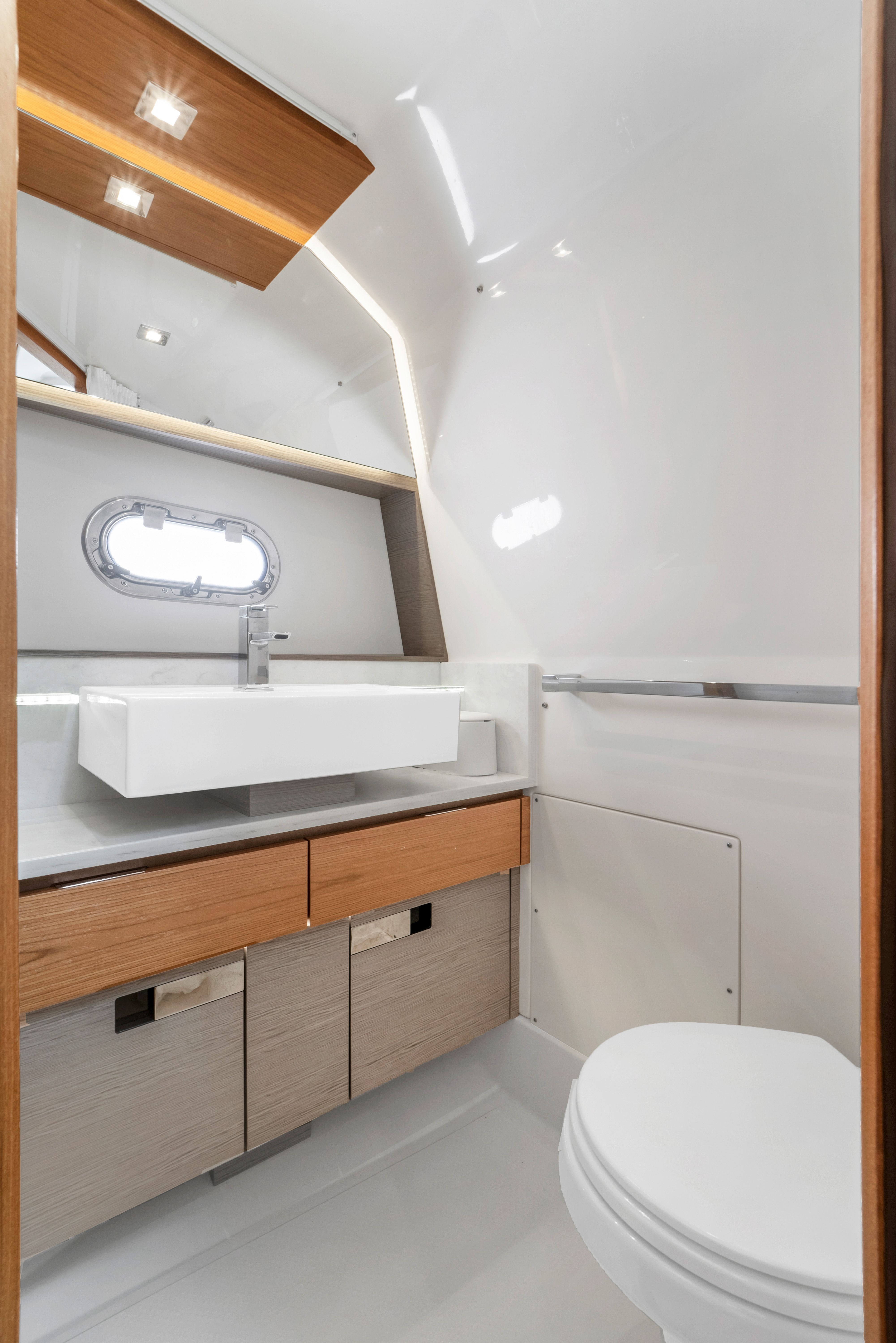 Modern bathroom with sink, mirror, and toilet inside a boat.