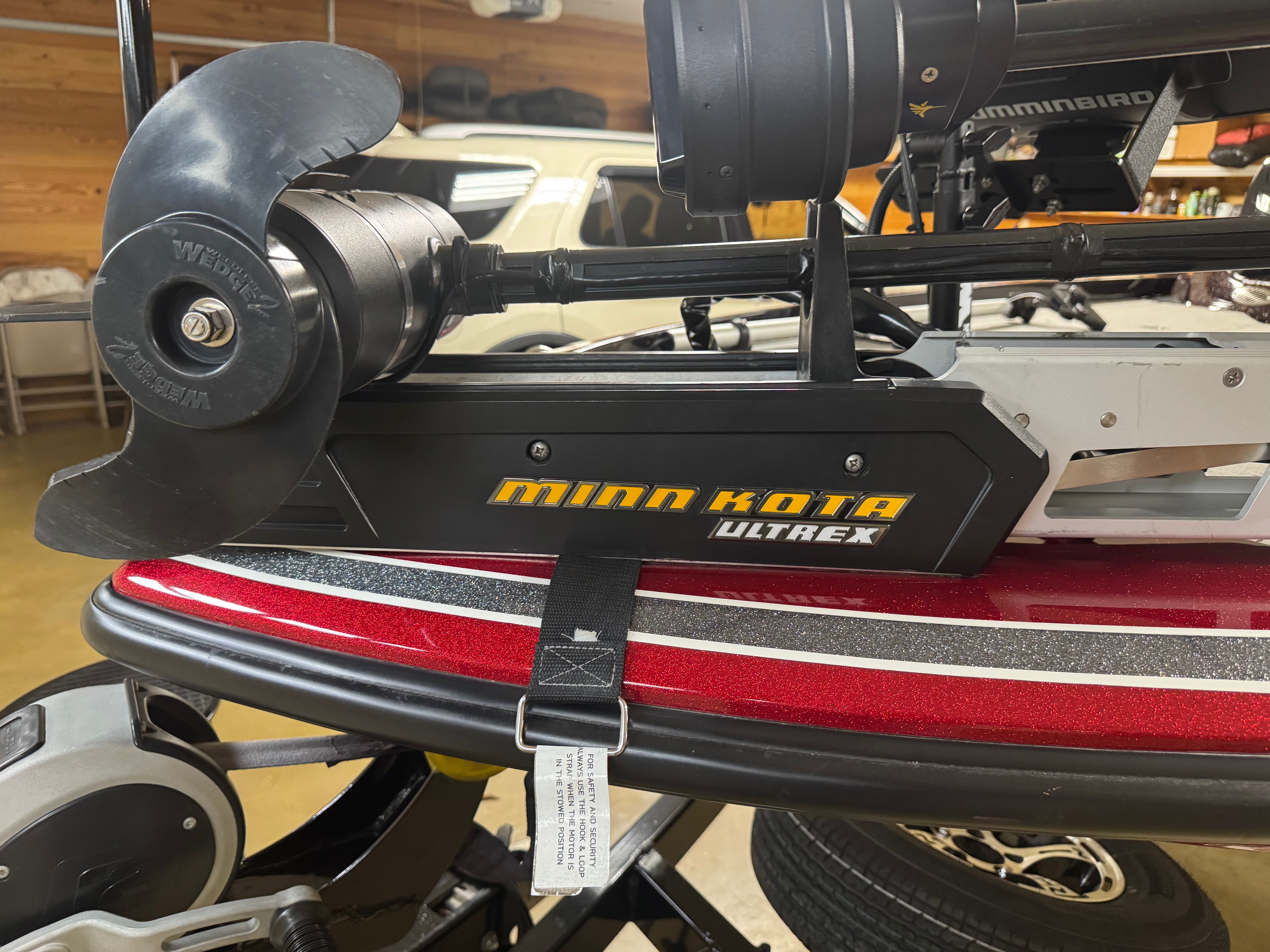 A red boat with a Minn Kota Ultrex motor in a garage.