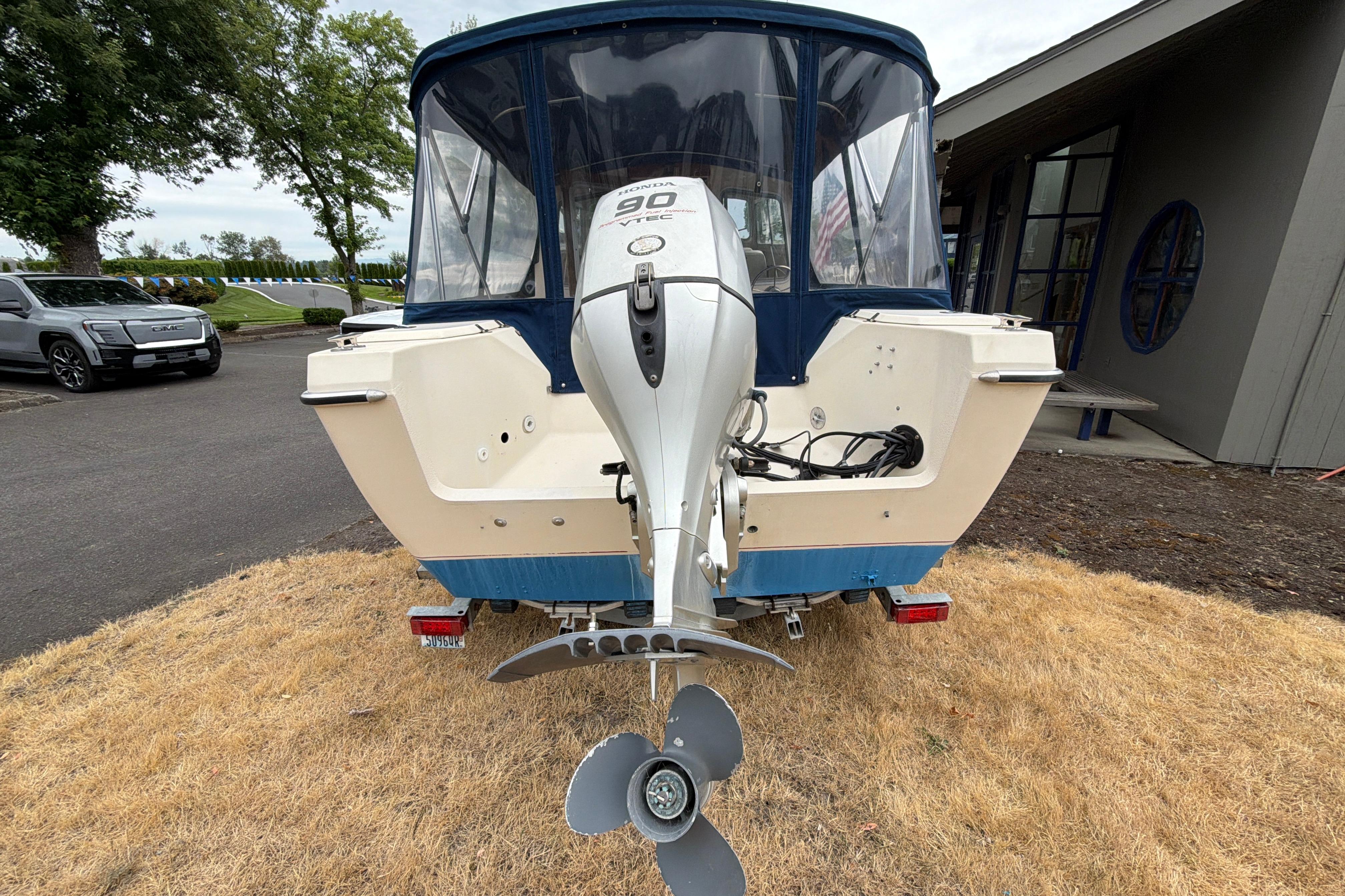 1989 C-Dory 22' Angler boat with Honda outboard motor, parked on dry grass.