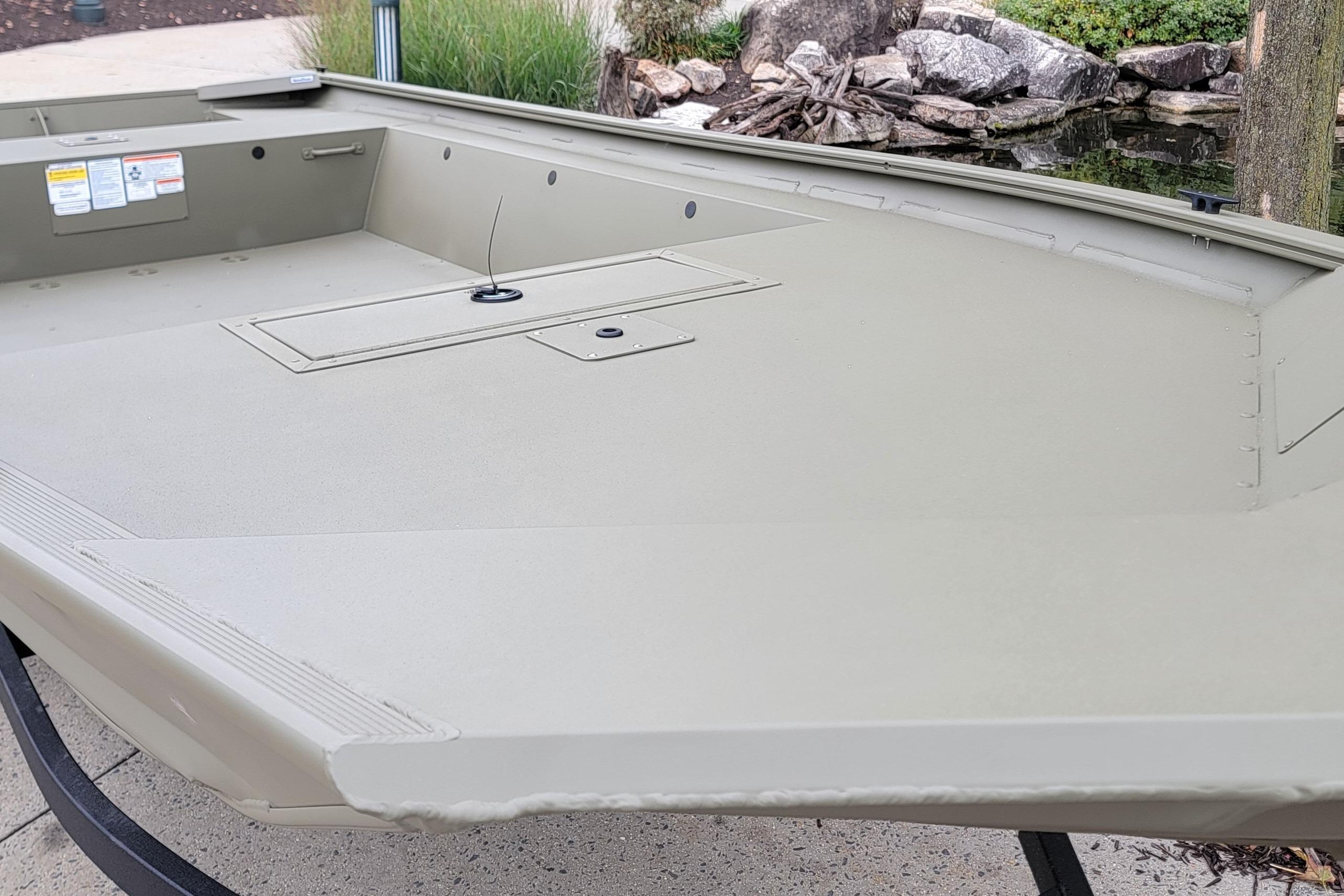 2026 Tracker Grizzly 1754 Utility boat, beige interior, near a pond with rocks.