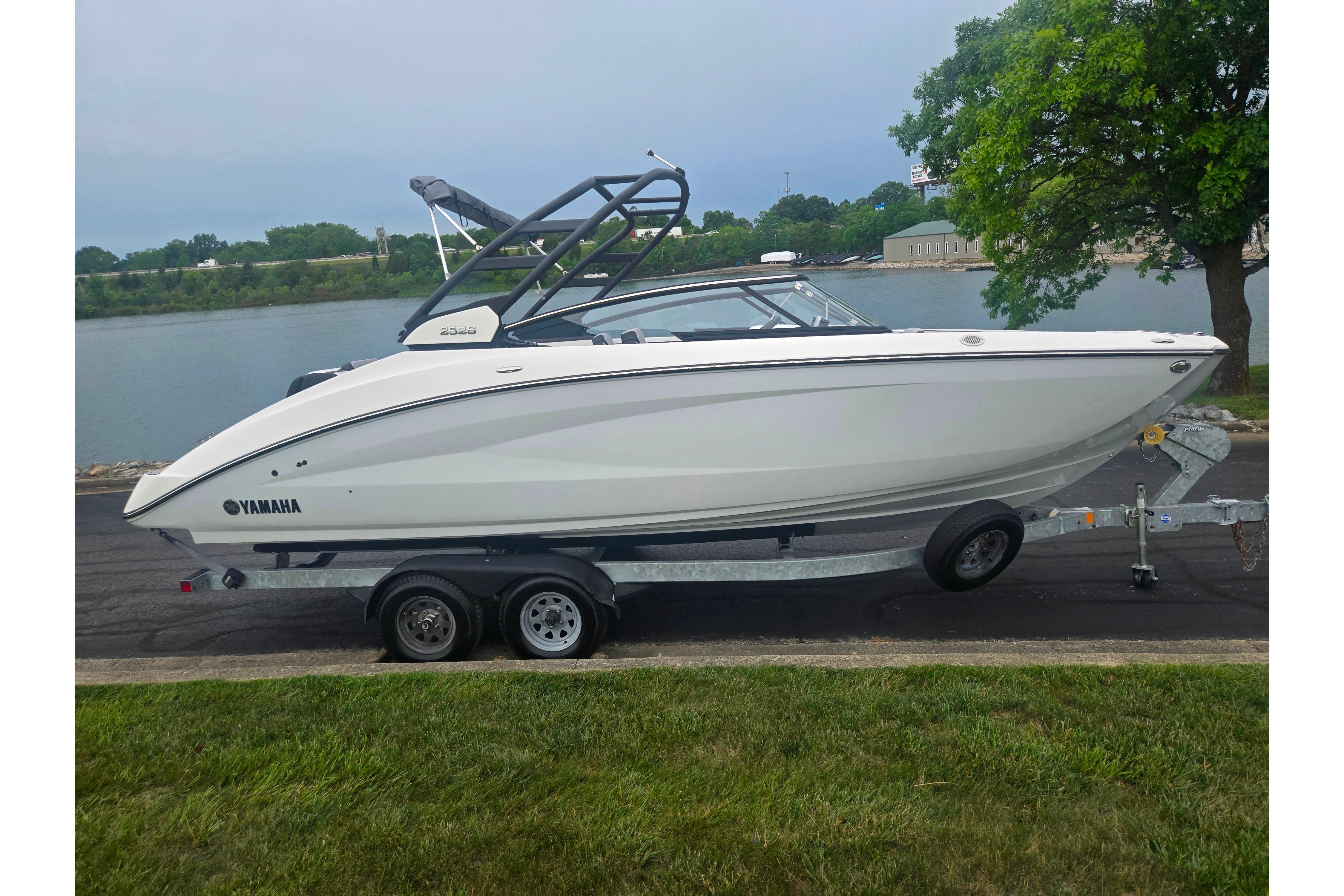 2023 Yamaha Boats 252S on trailer by a lakeside, showcasing sleek design and modern features.
