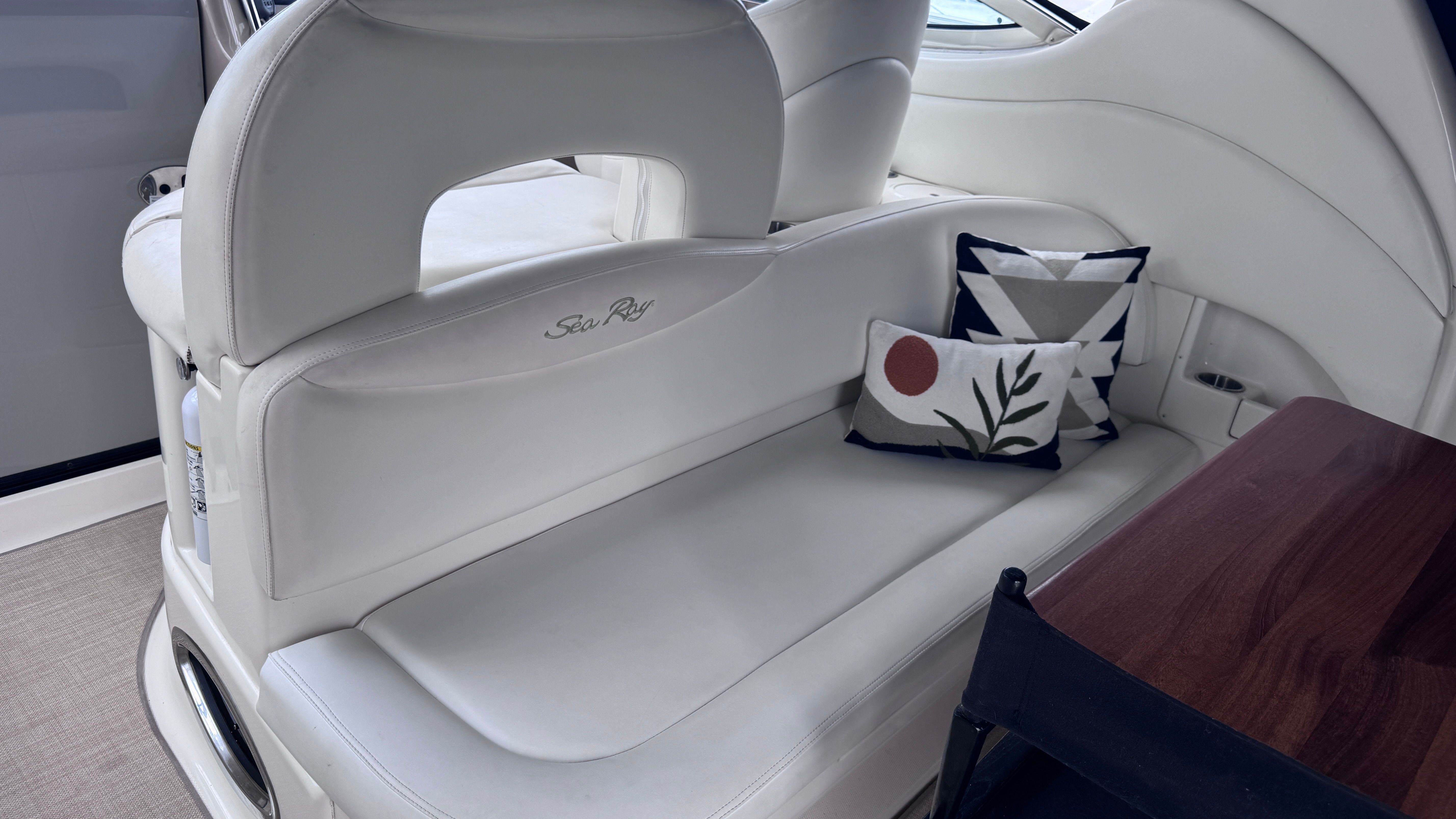 Interior of a 2003 Sea Ray 360 Sundancer with white upholstery and a decorative pillow.