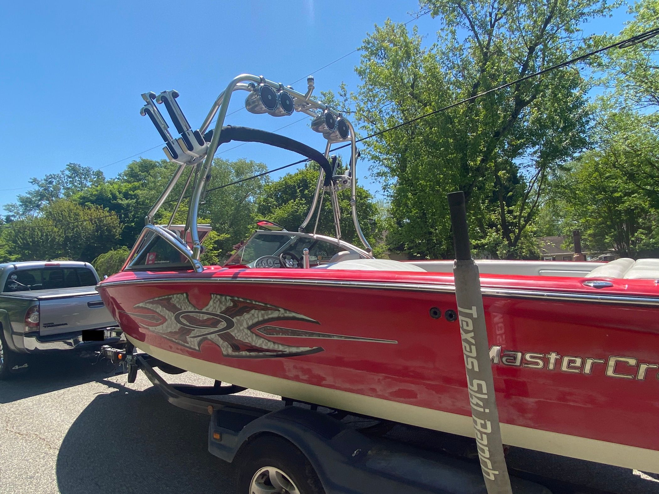 A red 2004 MasterCraft X-9 boat on a trailer, featuring a wakeboard tower.