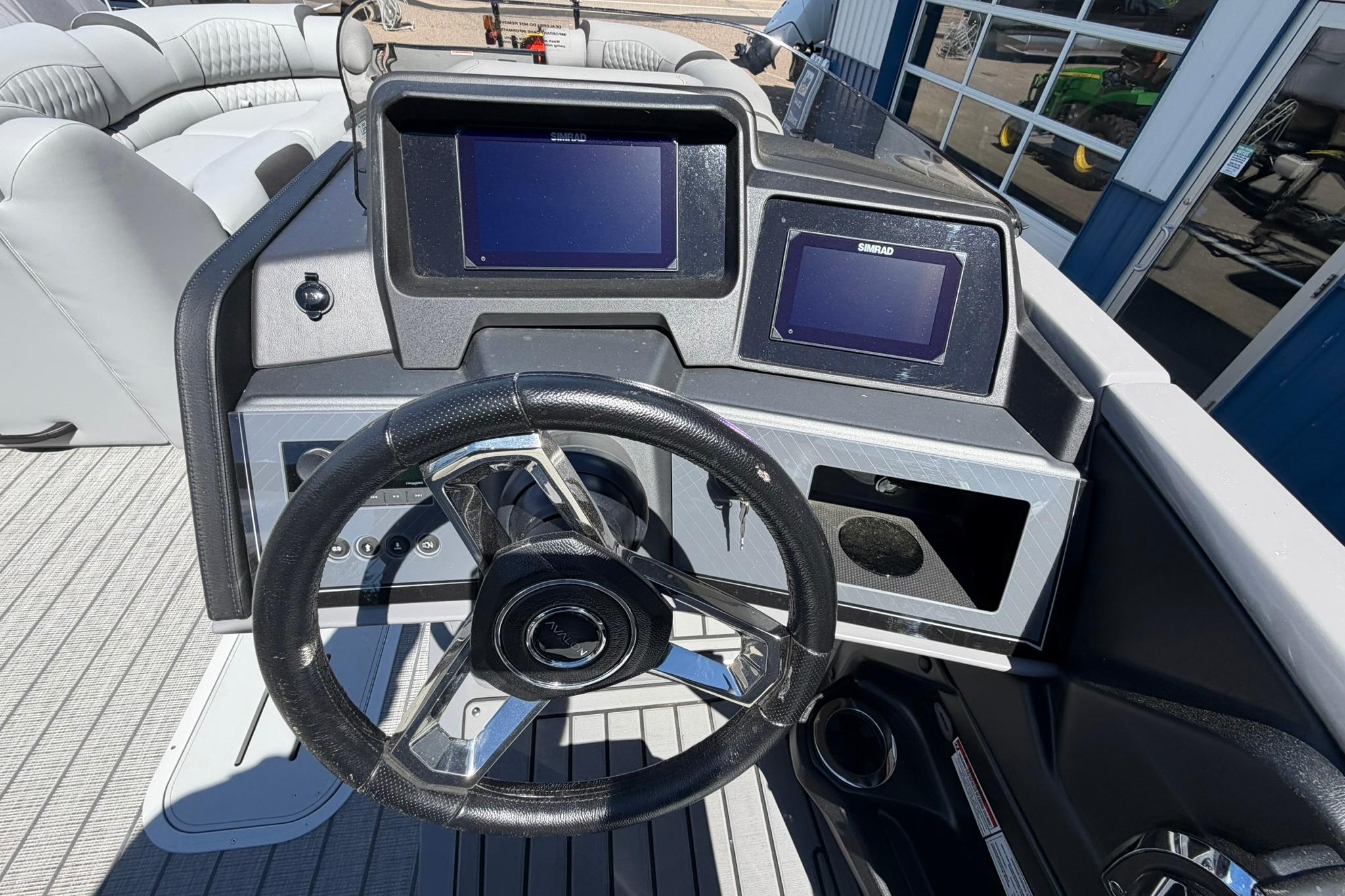 2026 Avalon Catalina Quad Lounge Shift boat dashboard with dual Simrad displays and steering wheel.