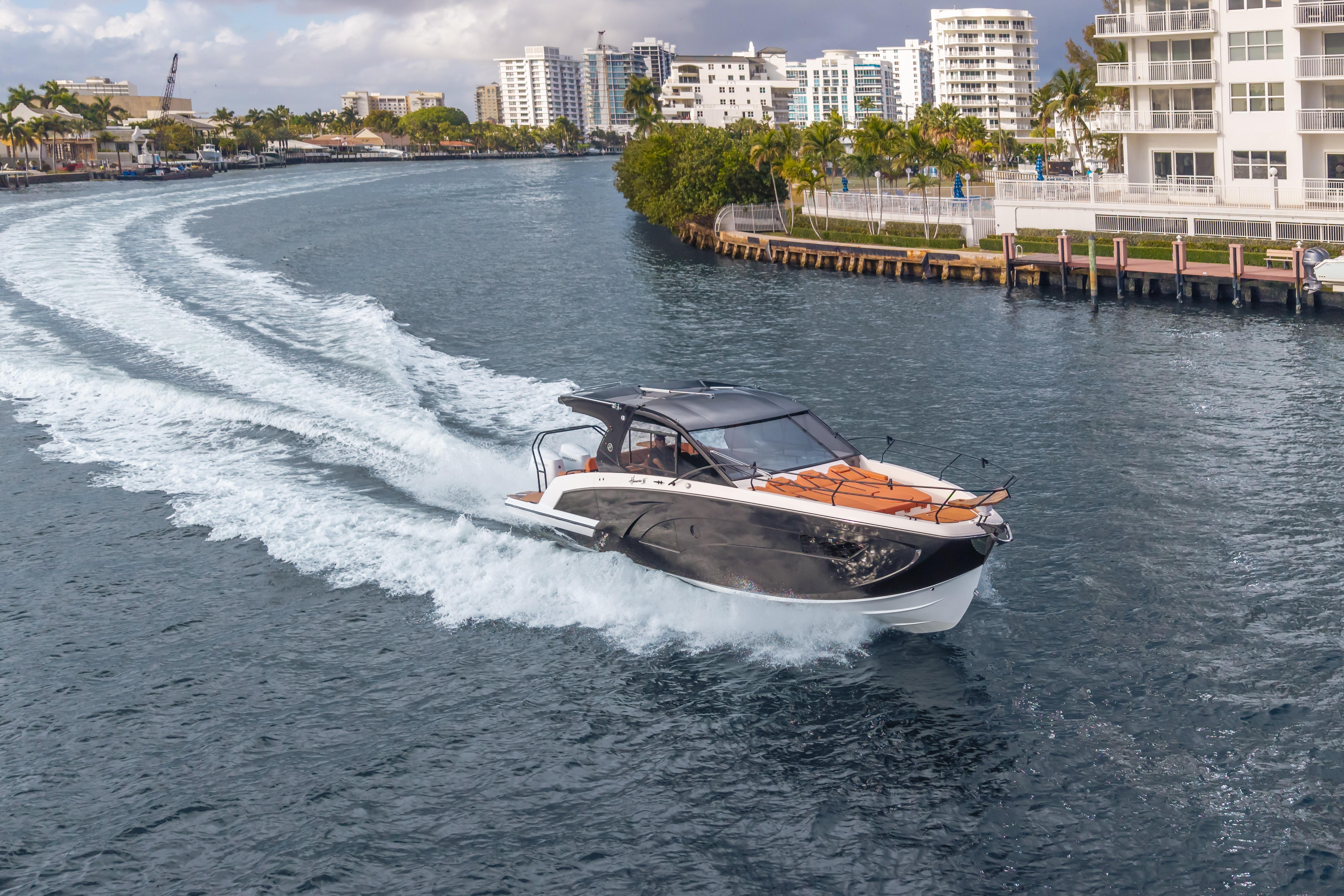2026 Hanover 387 yacht cruising in a scenic urban waterway with modern buildings.