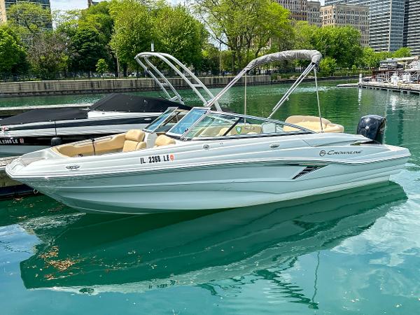 2023 Crownline 215 XS boat docked on a serene lake with lush greenery.