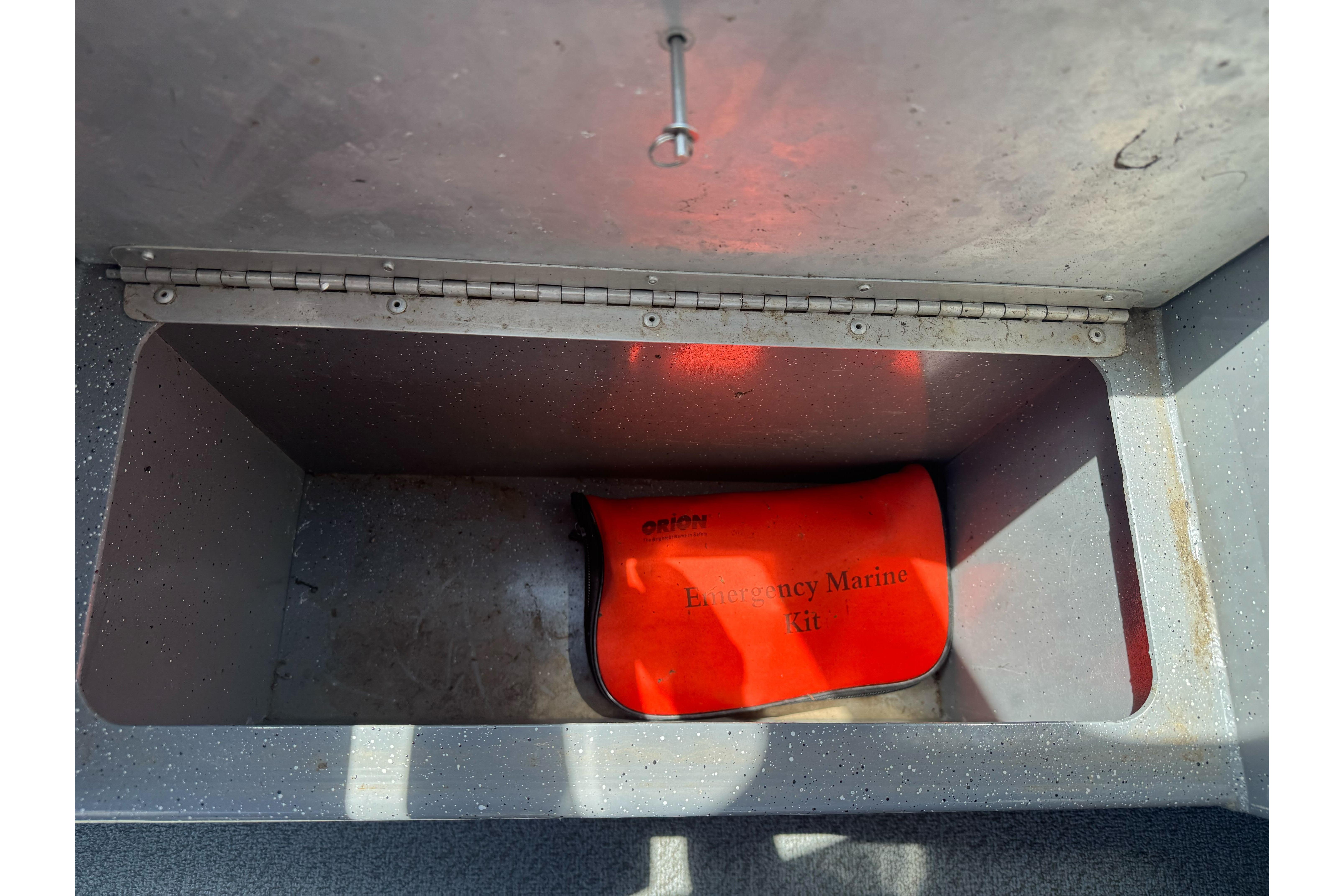 Open storage compartment with an emergency marine kit inside a 2014 River Hawk 19 GB boat.