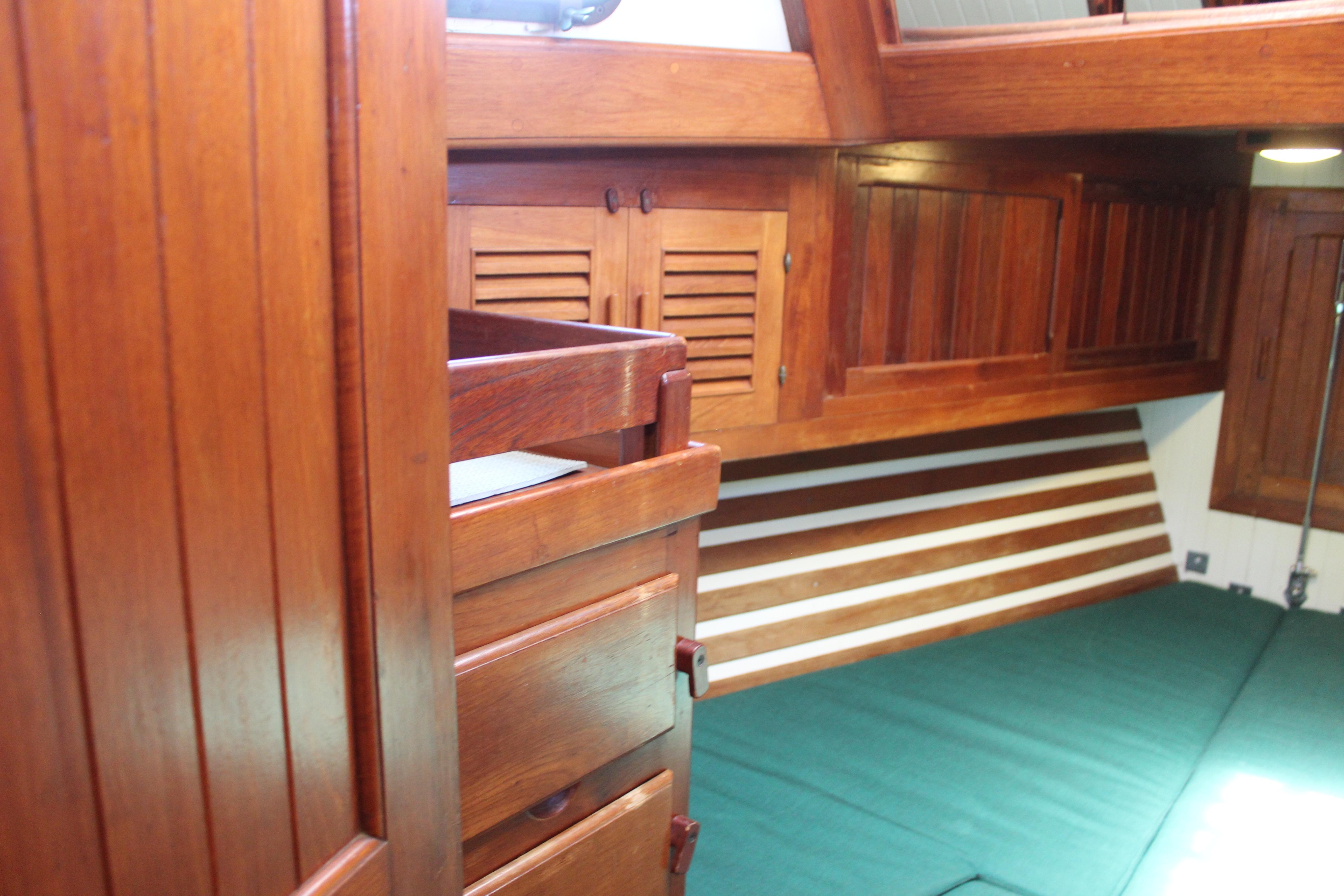 Interior of 1981 Kelly Peterson 46 sailboat with wooden cabinetry and green bedding.