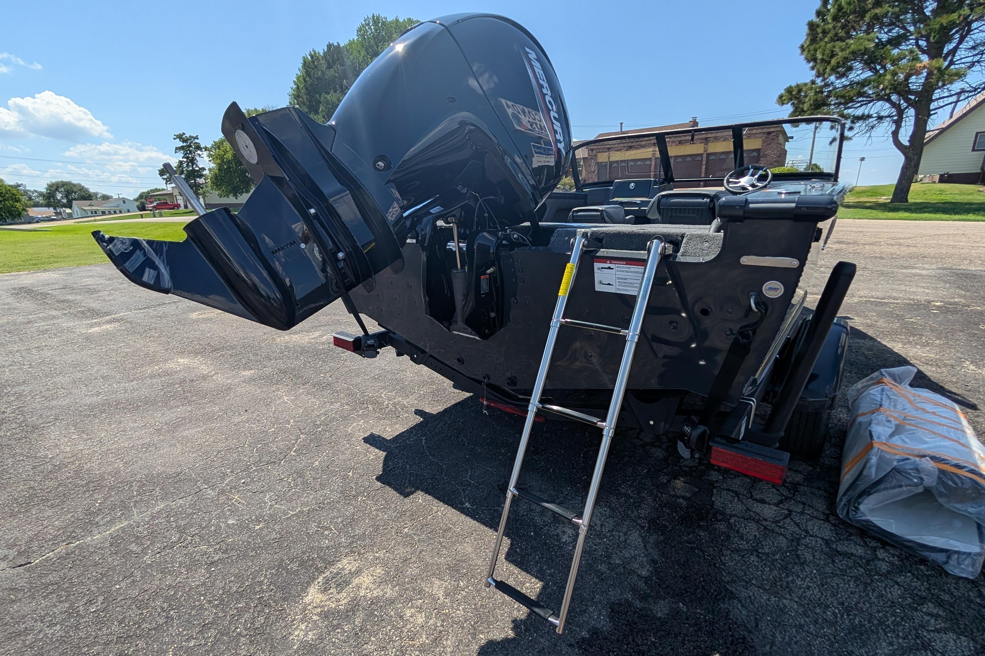 2026 Lund 1875 Crossover XS boat with ladder and outboard motor on pavement.