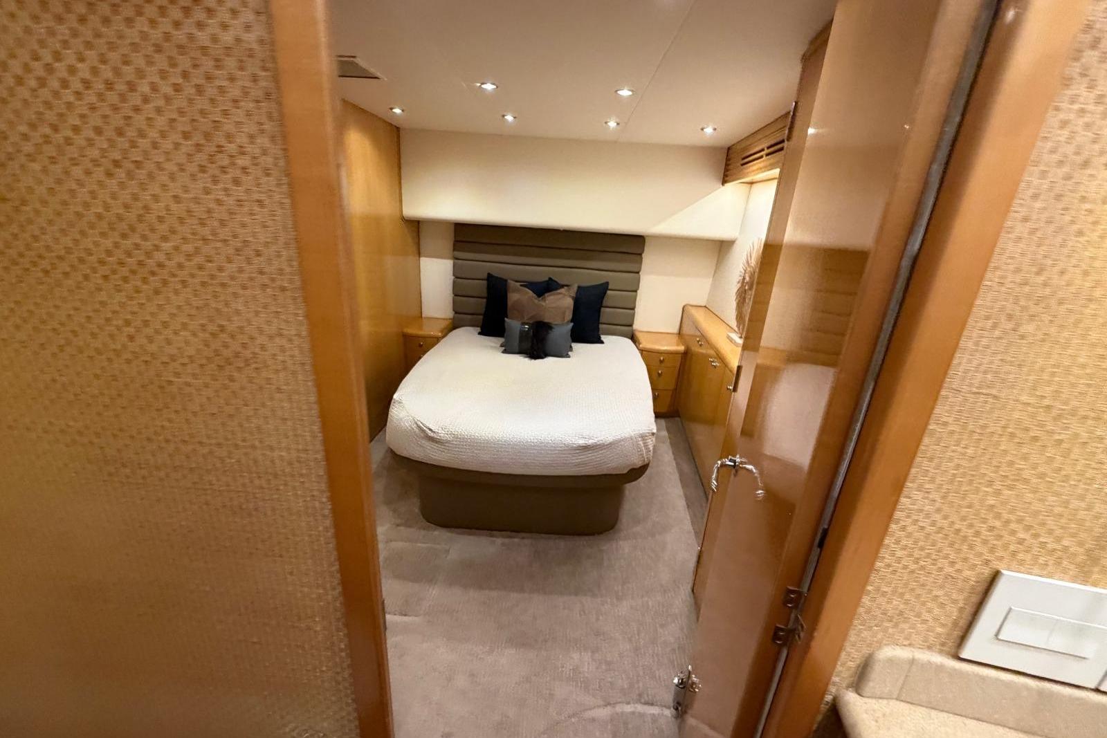 Luxurious bedroom interior of 2003 Hatteras 54 Convertible yacht with cozy bed and elegant decor.