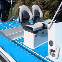 Two cushioned seats on a blue boat with a white deck.