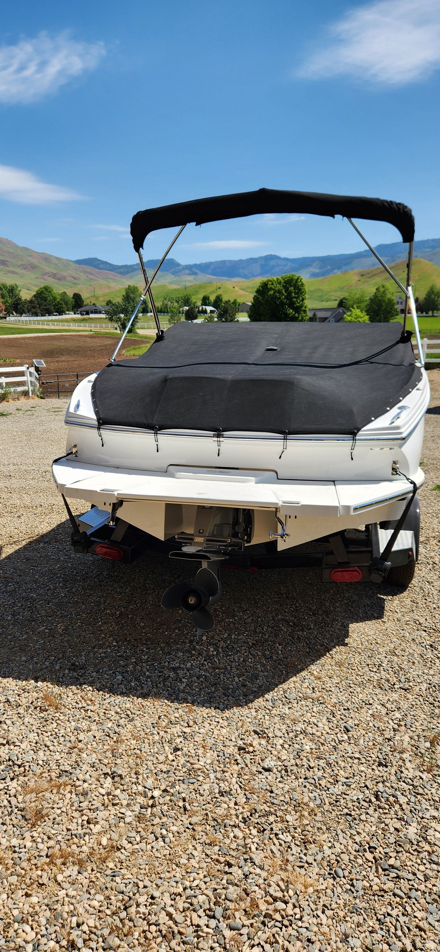 A Cobalt CS22 boat is on a trailer in a gravel area.