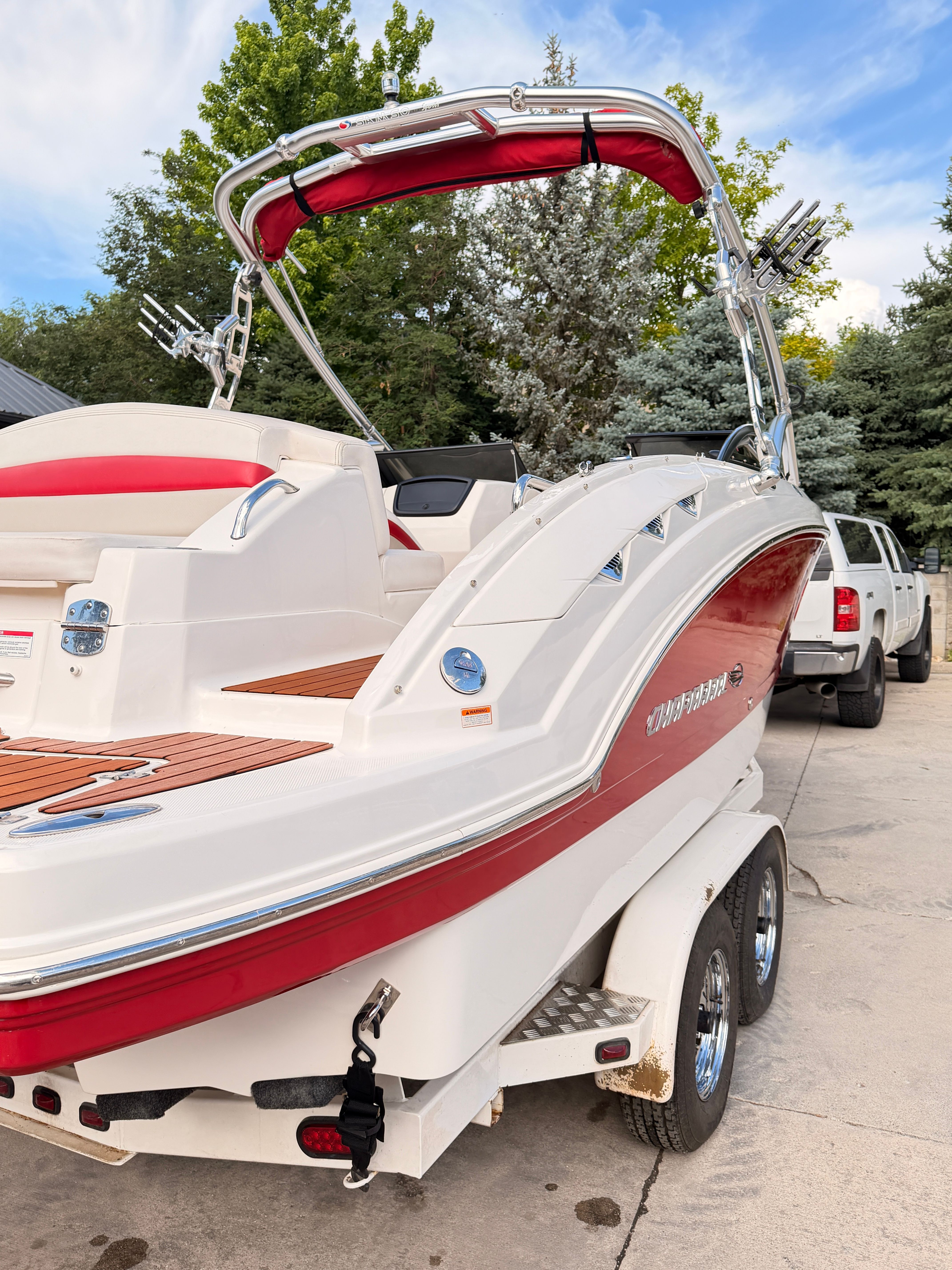 A 2008 Chaparral Sunesta 224 boat on a trailer. It features red accents and a Bimini top.