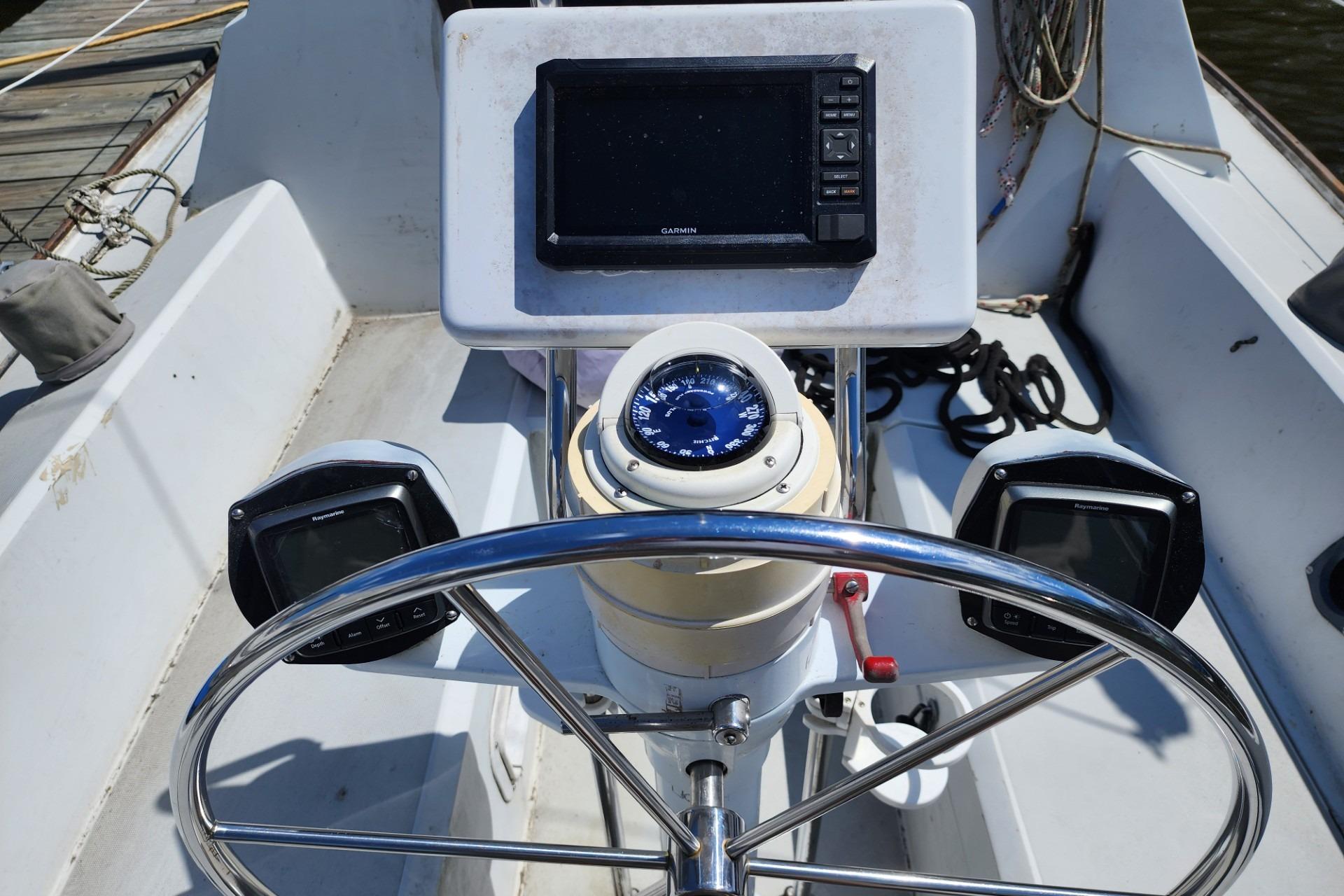 Cockpit of 1988 O'Day 272 LE sailboat with steering wheel, compass, and navigation equipment.