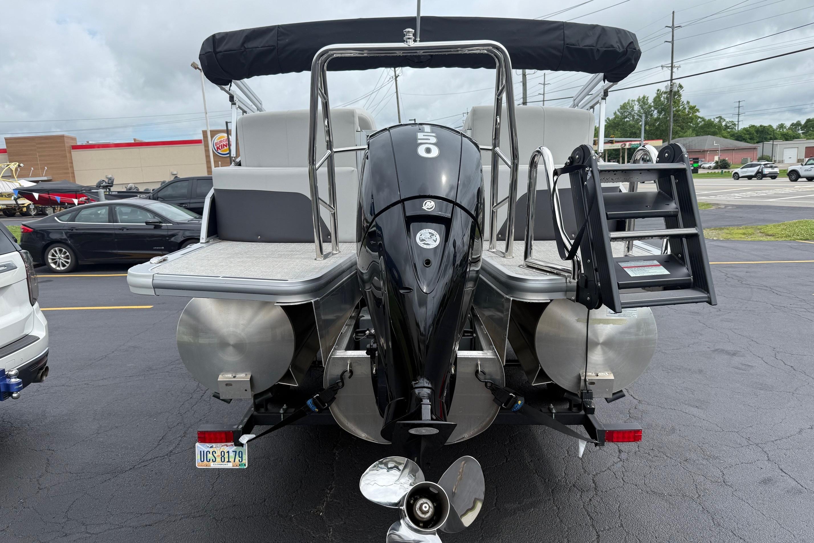 2025 Harris Cruiser 230 pontoon boat with outboard motor in parking lot.