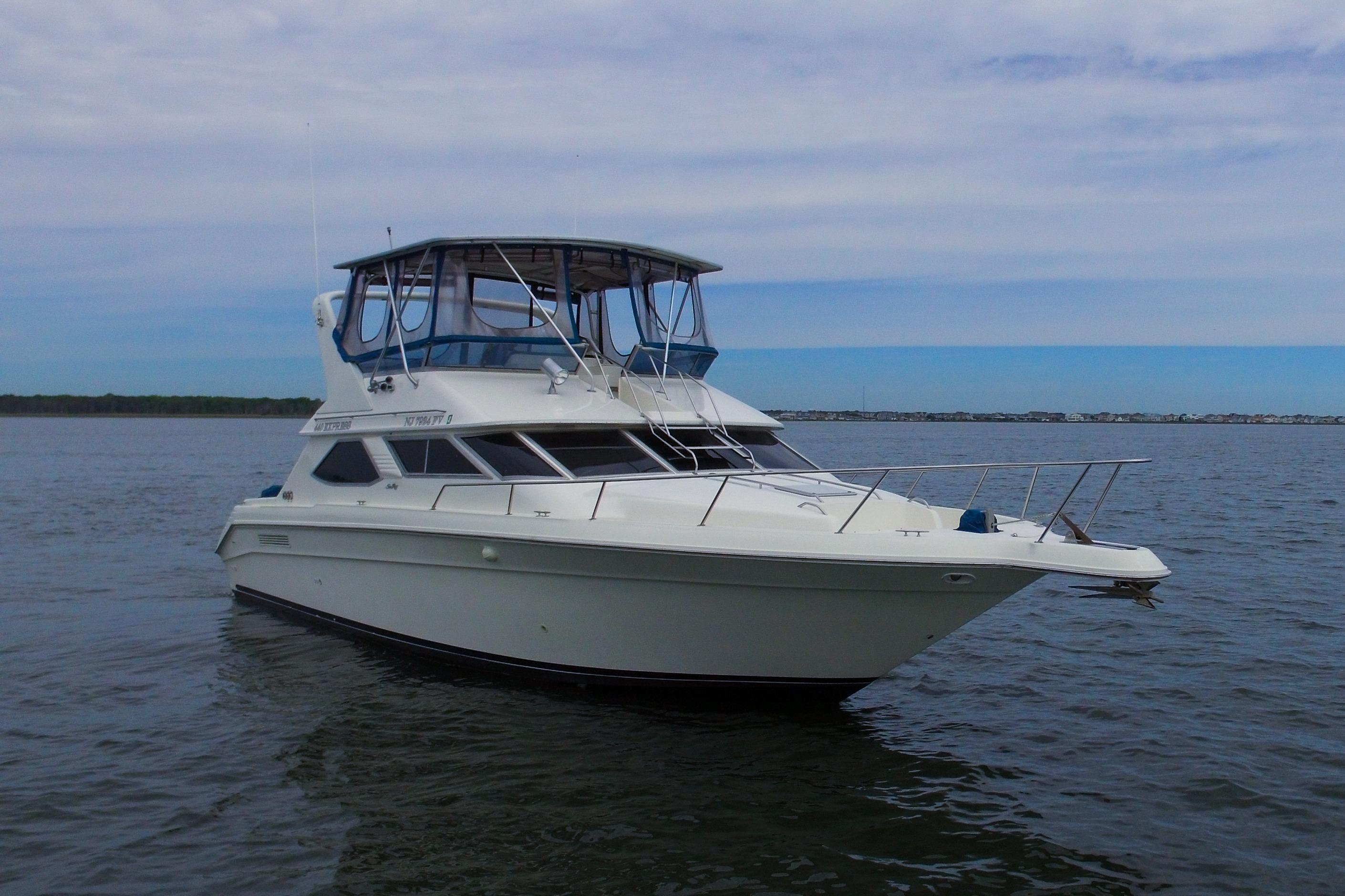 1993 Sea Ray 440 Express Bridge yacht on calm water under a cloudy sky.