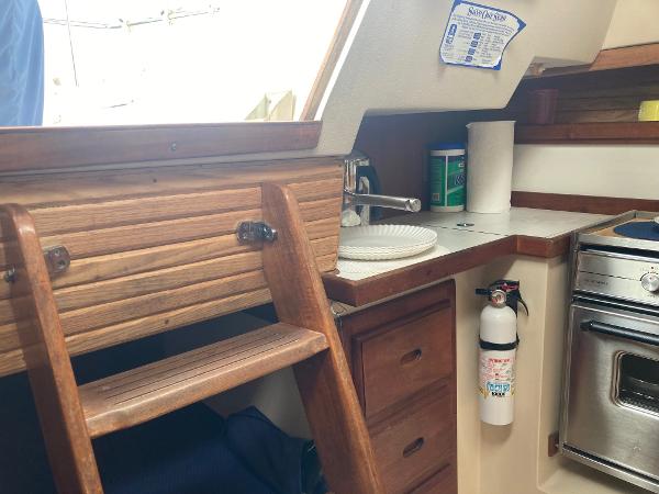 Interior of 1989 Catalina 30 sailboat with wooden cabinetry and compact kitchen area.
