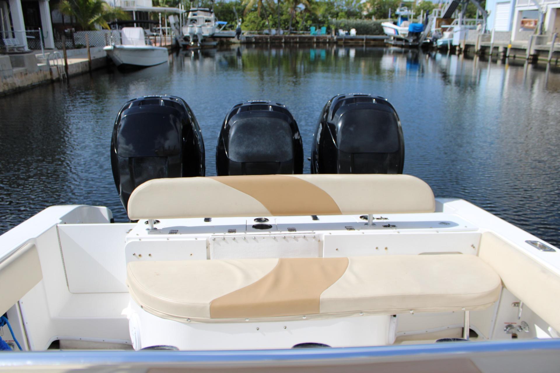 2007 Fountain 34 Center Console boat with triple outboard engines docked in a serene marina.