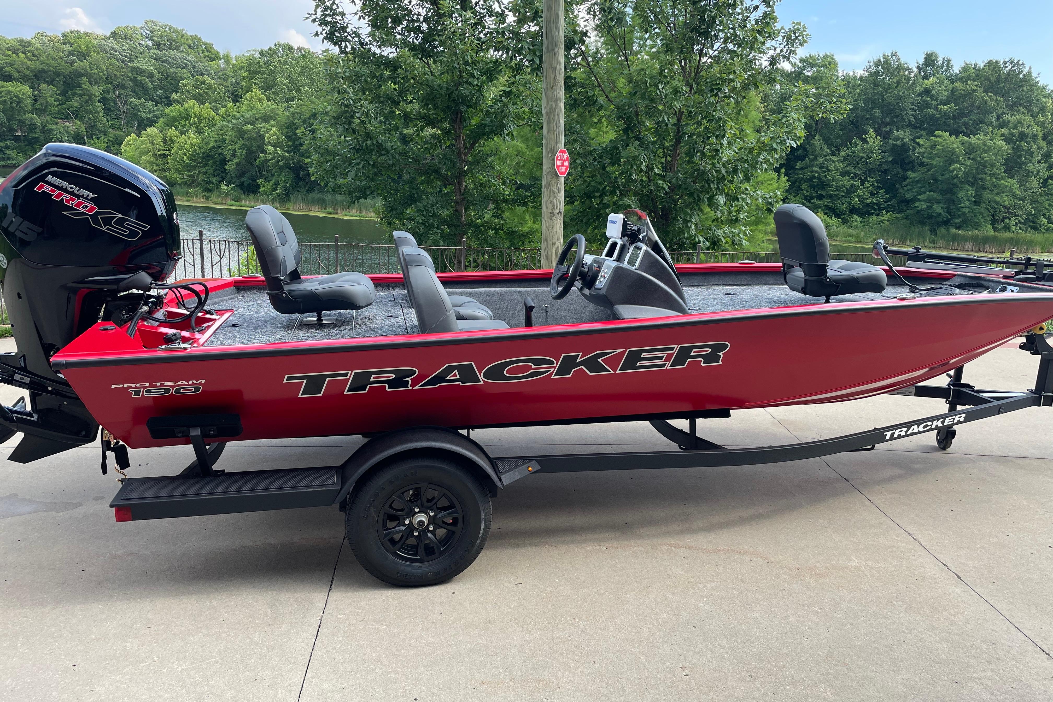 2026 Tracker Pro Team 190 boat on trailer, red exterior, parked near a lake.